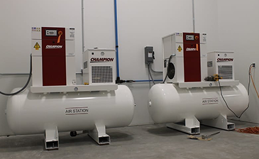 Worker wearing a white hard hat and gloves installing a security camera on a ceiling.