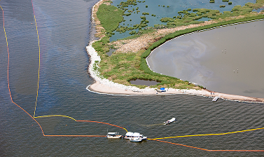 Aerial view of a river bend with boats near a small sandy shore and green vegetation along the water.