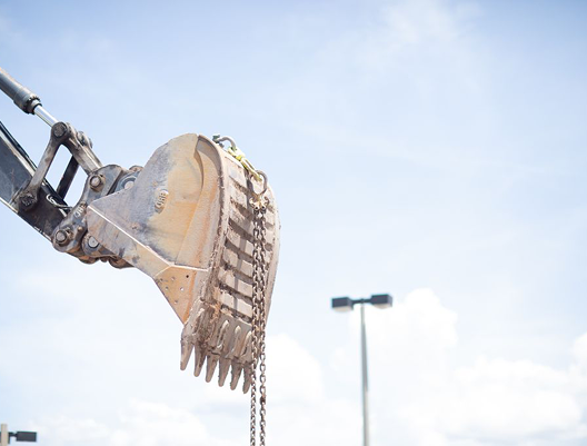 Person wearing a safety vest handling plastic packaging inside an open cardboard box on a table with electronic equipment nearby.