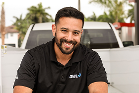 Two construction workers wearing safety gear and blue gloves examining a broken concrete piece with exposed cables on the ground.