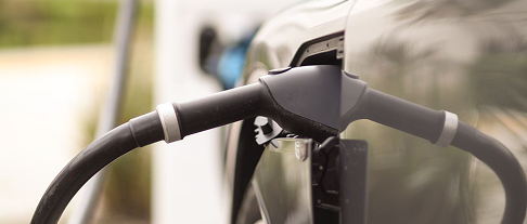 Electric vehicle being charged with a charging cable plugged into the car.