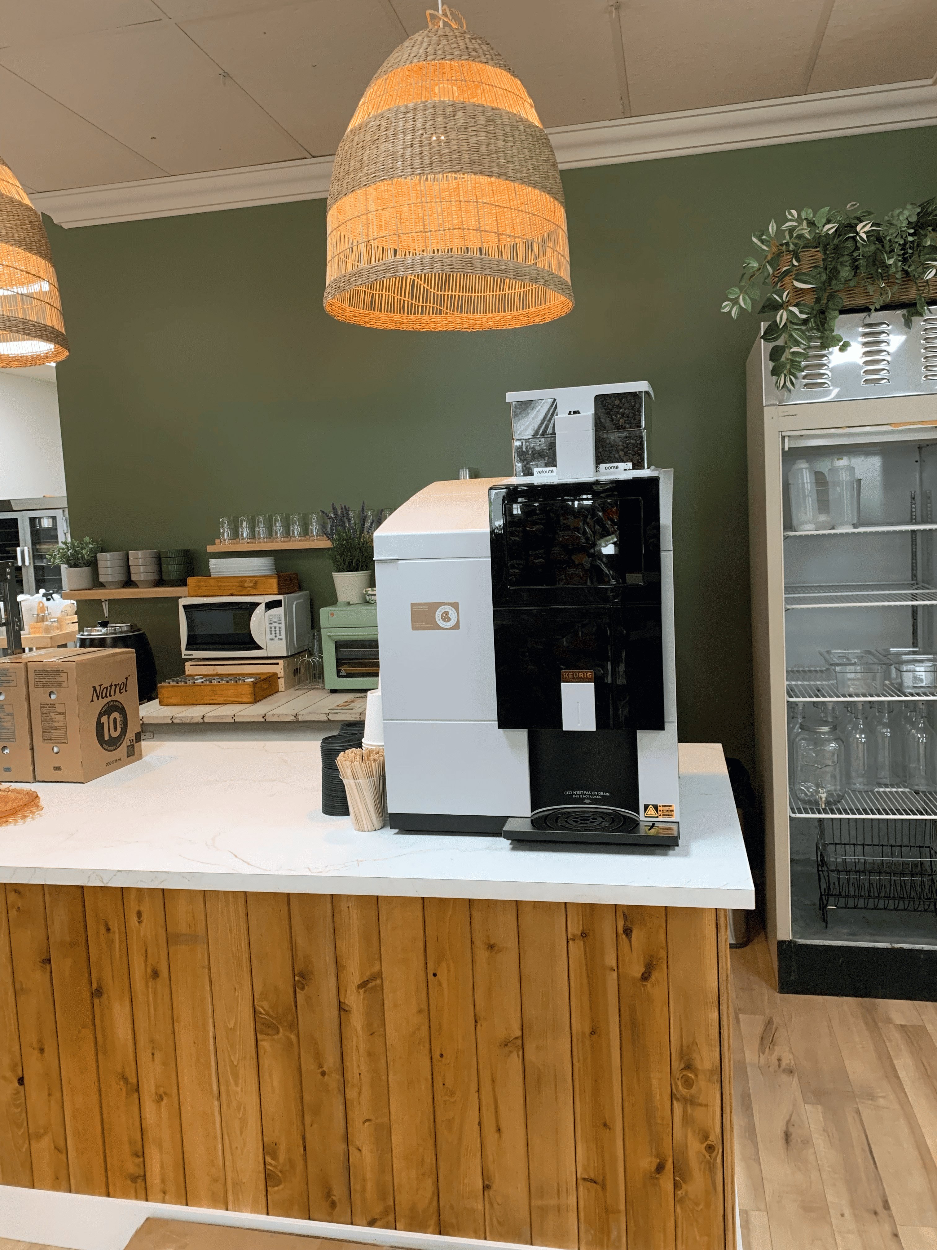 Machine à café noire et blanche sur un comptoir en bois clair dans un café moderne.