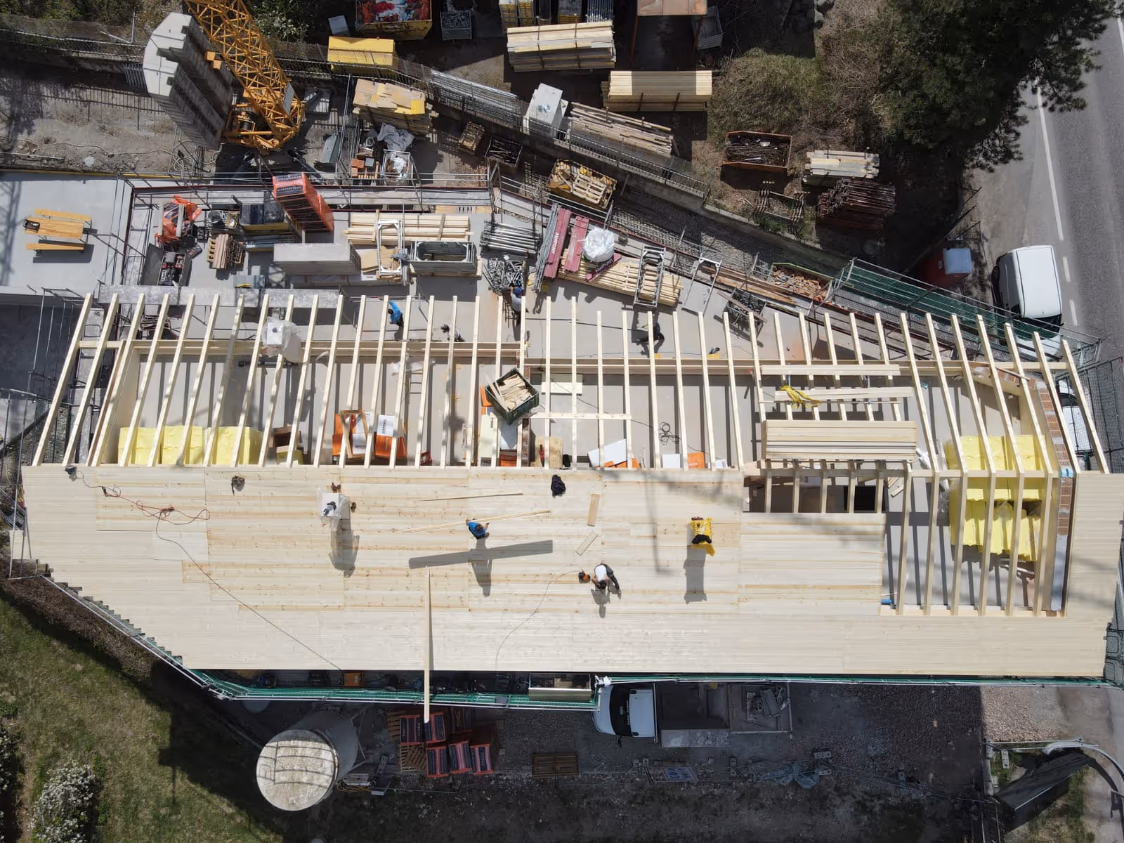 Luftaufnahme einer Dachkonstruktion mit Holzrahmenbau und Arbeitern auf der Baustelle.