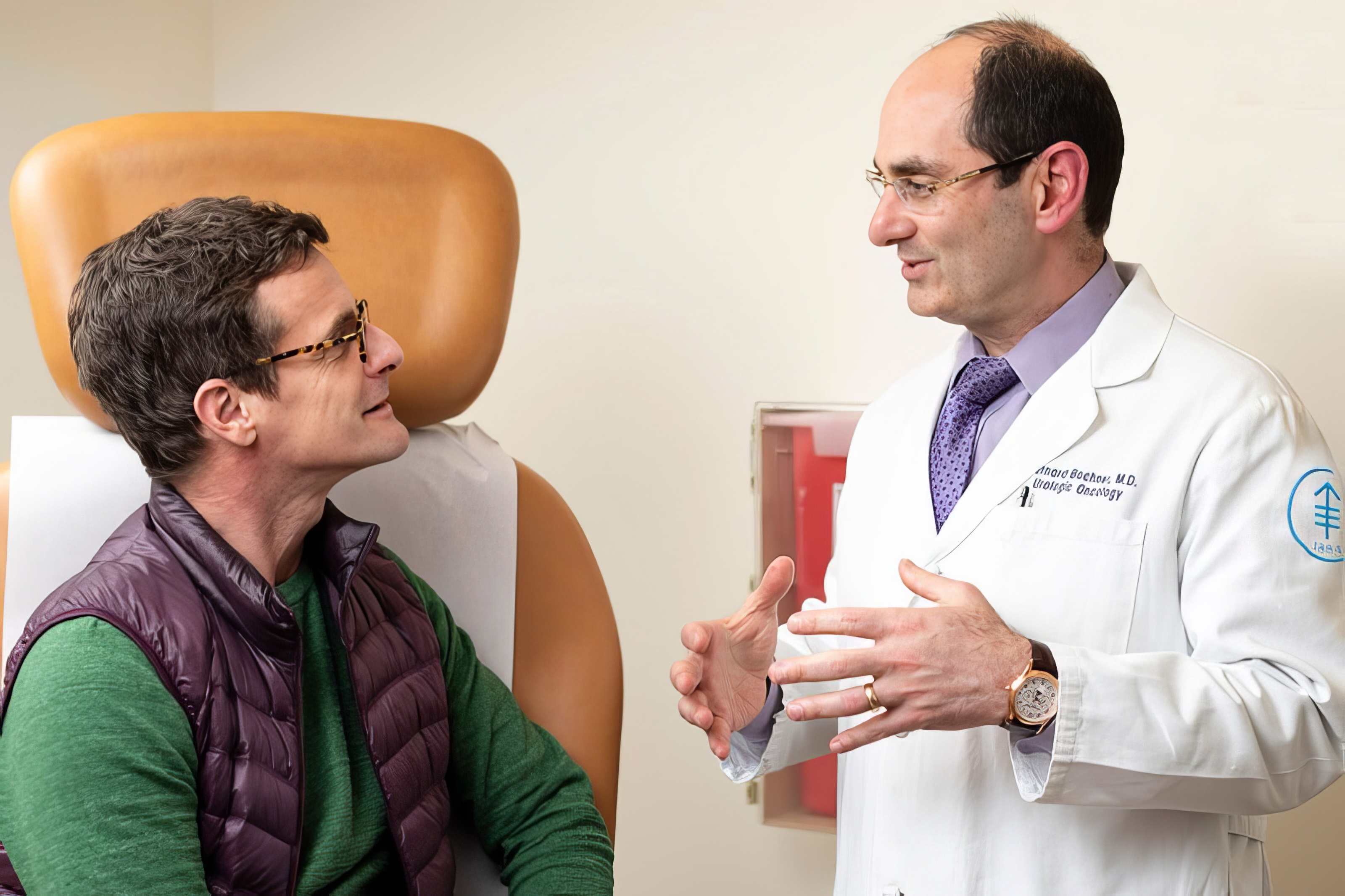 Doctor Bochner, Memorial Sloan Kettering in white coat speaking with male patient seated in a tan medical chair.