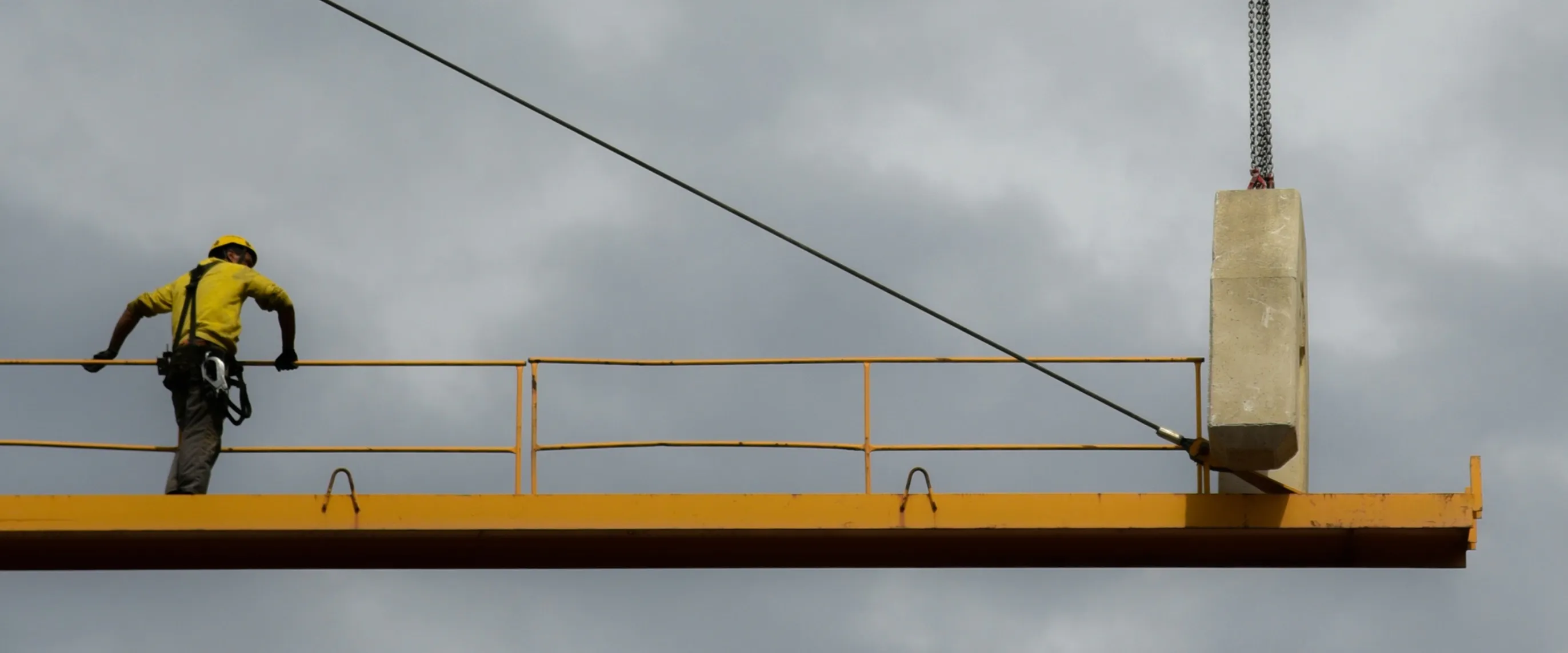 Construction worker on a suspended beam with safety harness — real estate and infrastructure