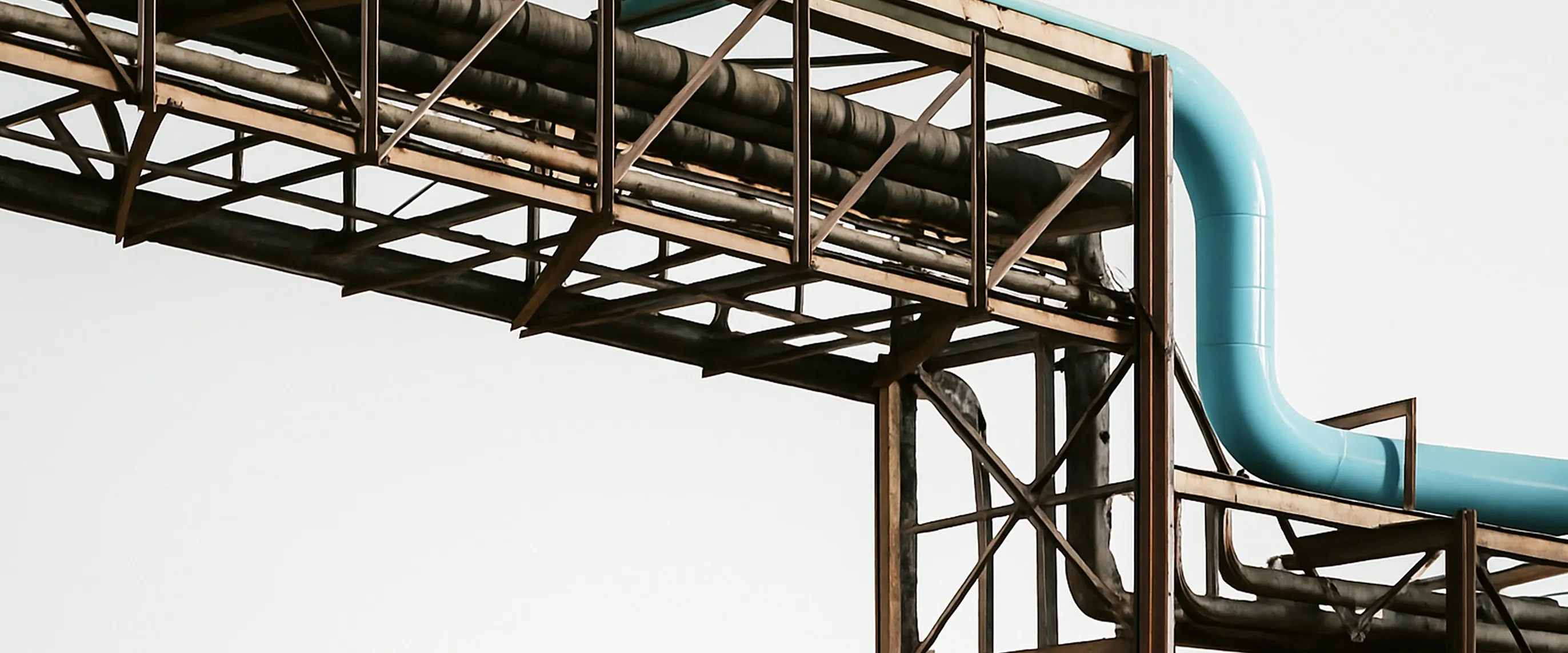 Industrial oil and gas pipeline with blue elbow against a pale sky — midstream infrastructure