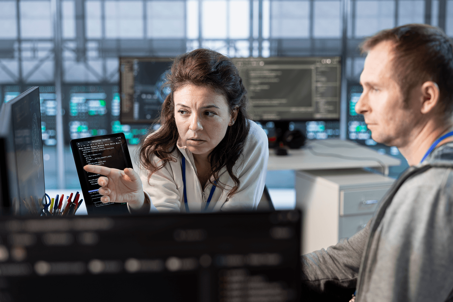 Engineers reviewing code on a tablet during a legacy system migration discussion.