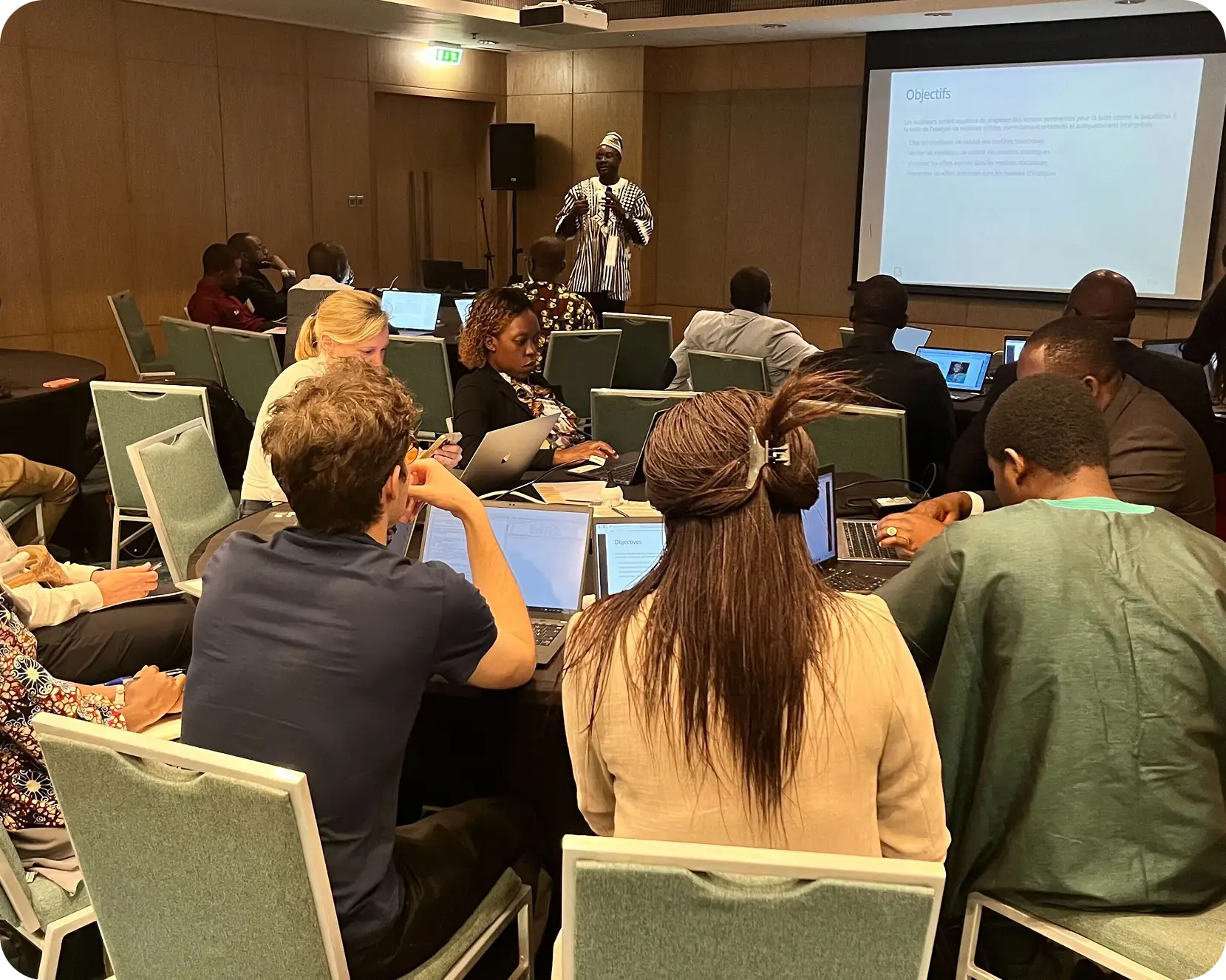 a group of people sitting around a table with laptops