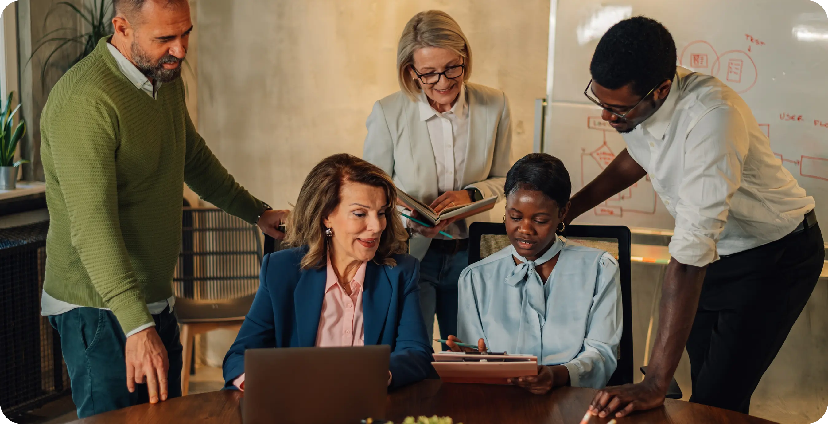 a group of people around a table looking at a laptop