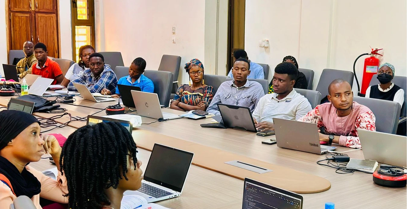 a group of people sitting at a table with laptops