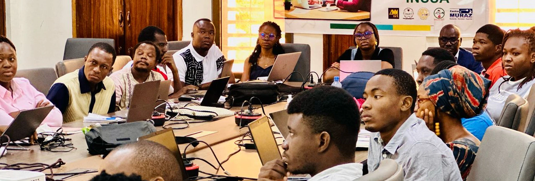 a group of people sitting around a table with laptops
