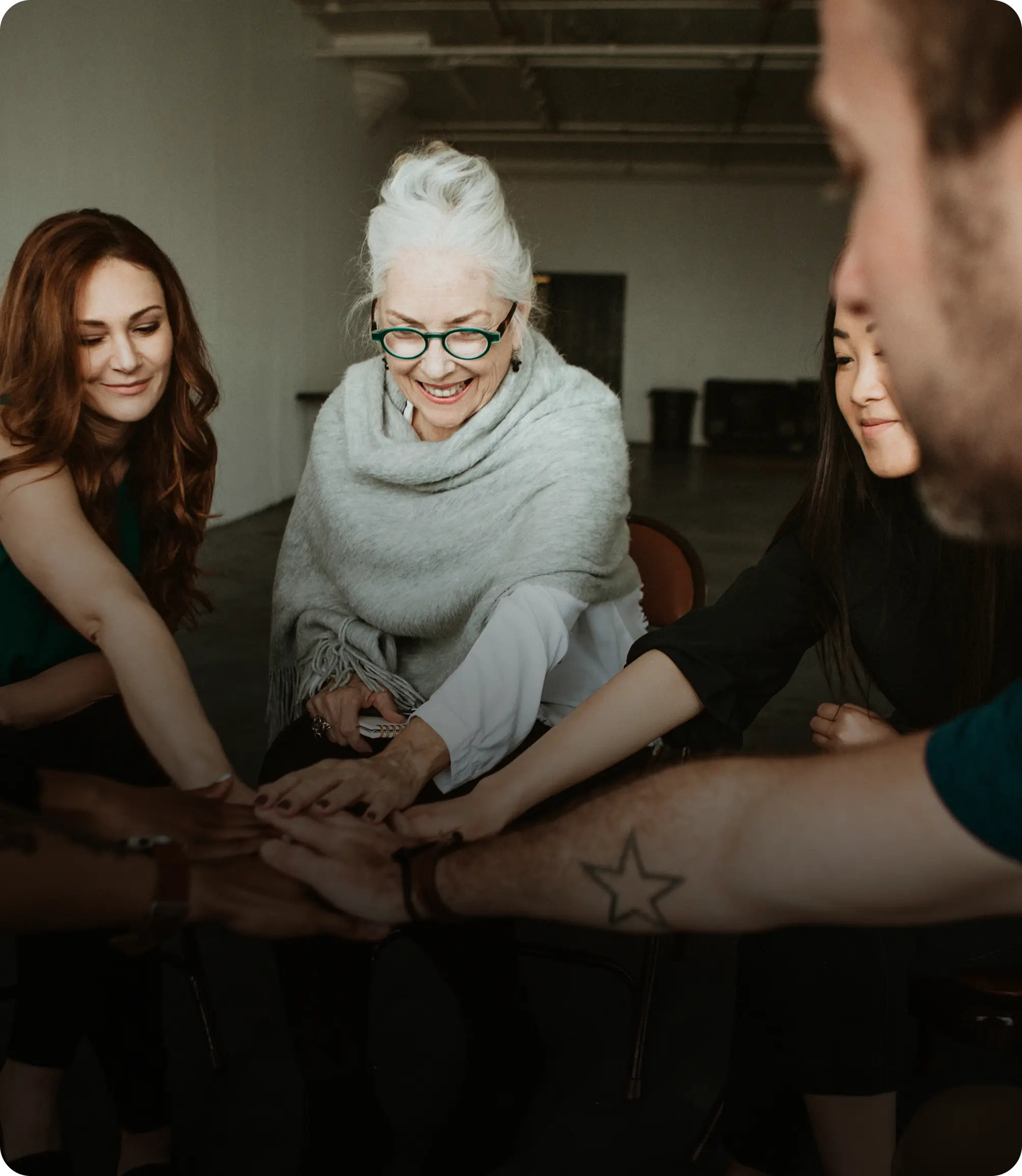 A group of people sitting around a table holding hands.