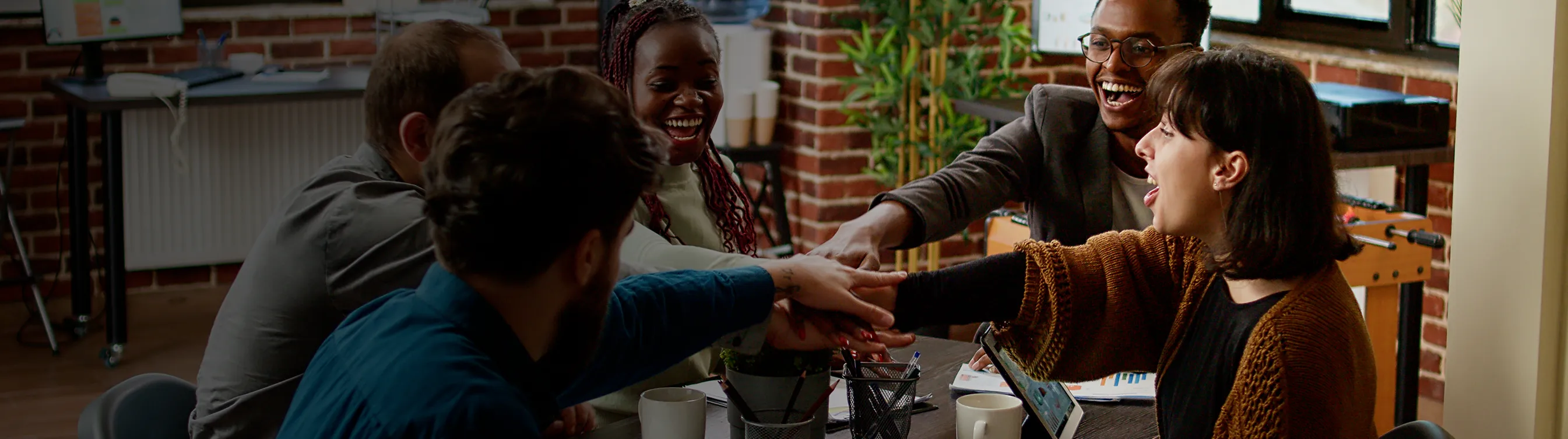 A group of people sitting around a table shaking hands.