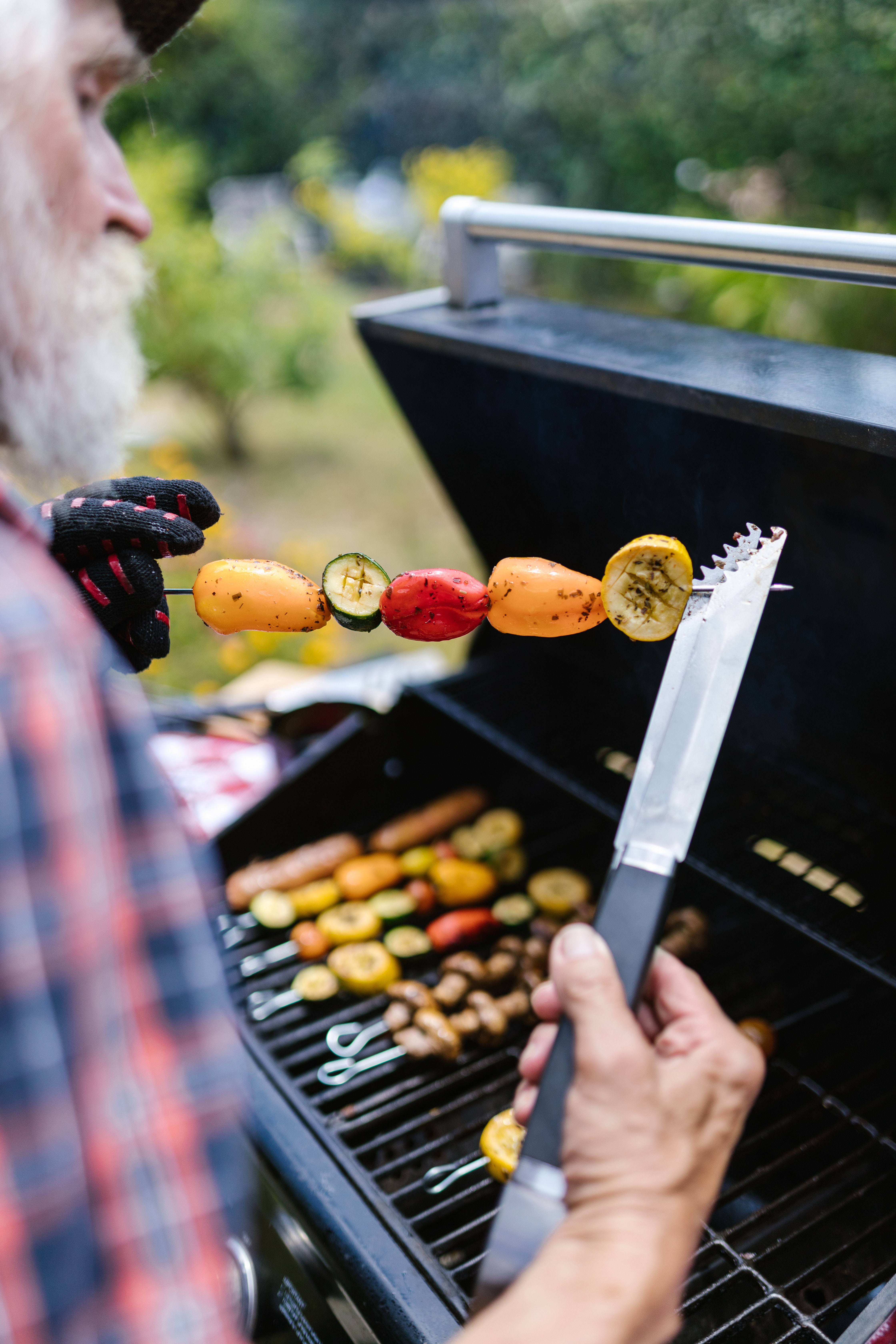 Vegetables on a skewer being held above a grill