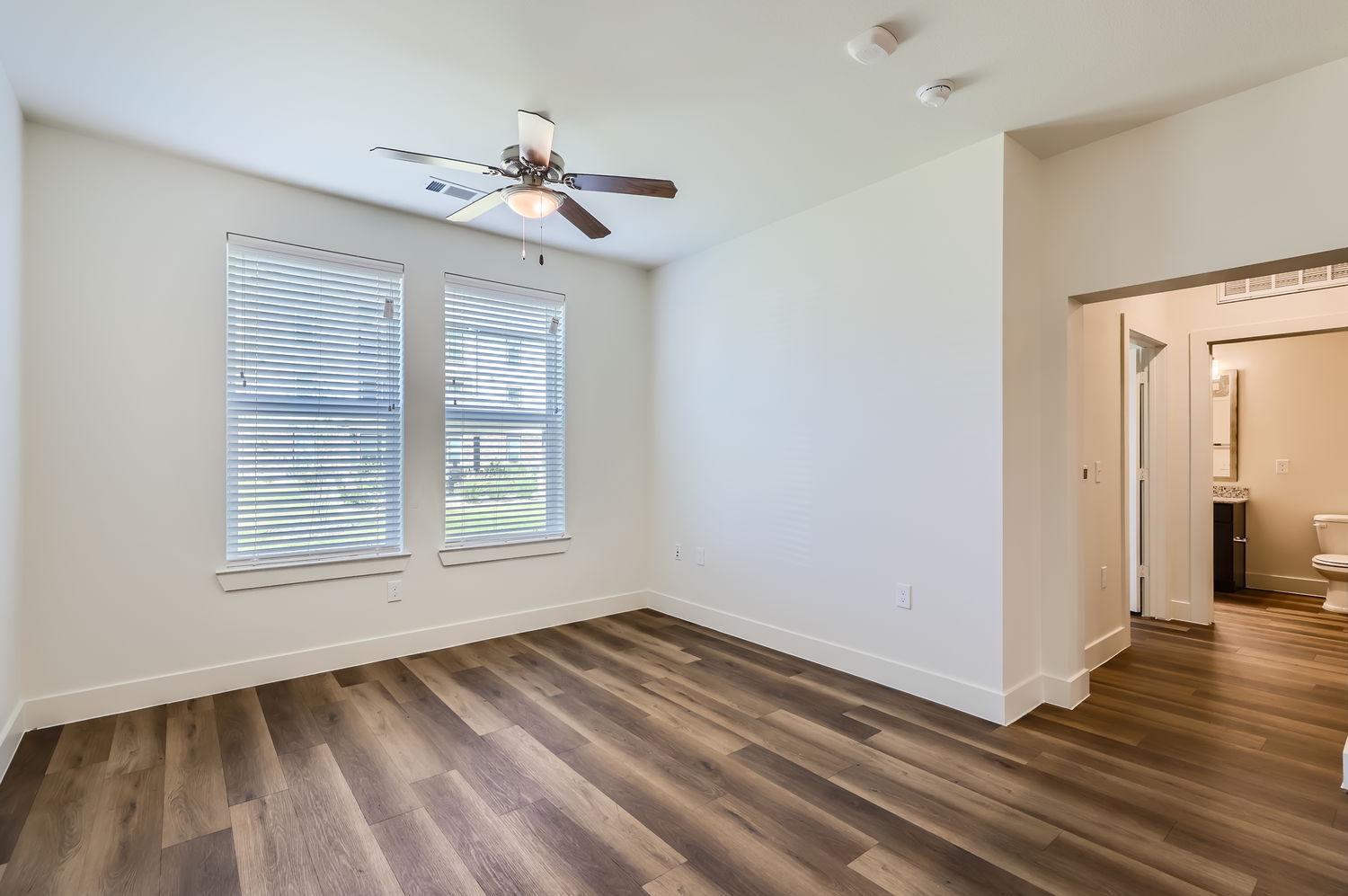 View of room with two windows leading into bathroom