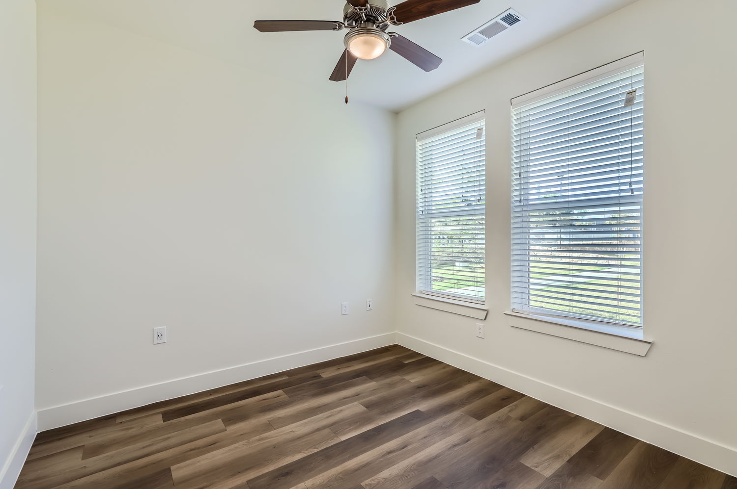 Empty room with ceiling fan and two windows