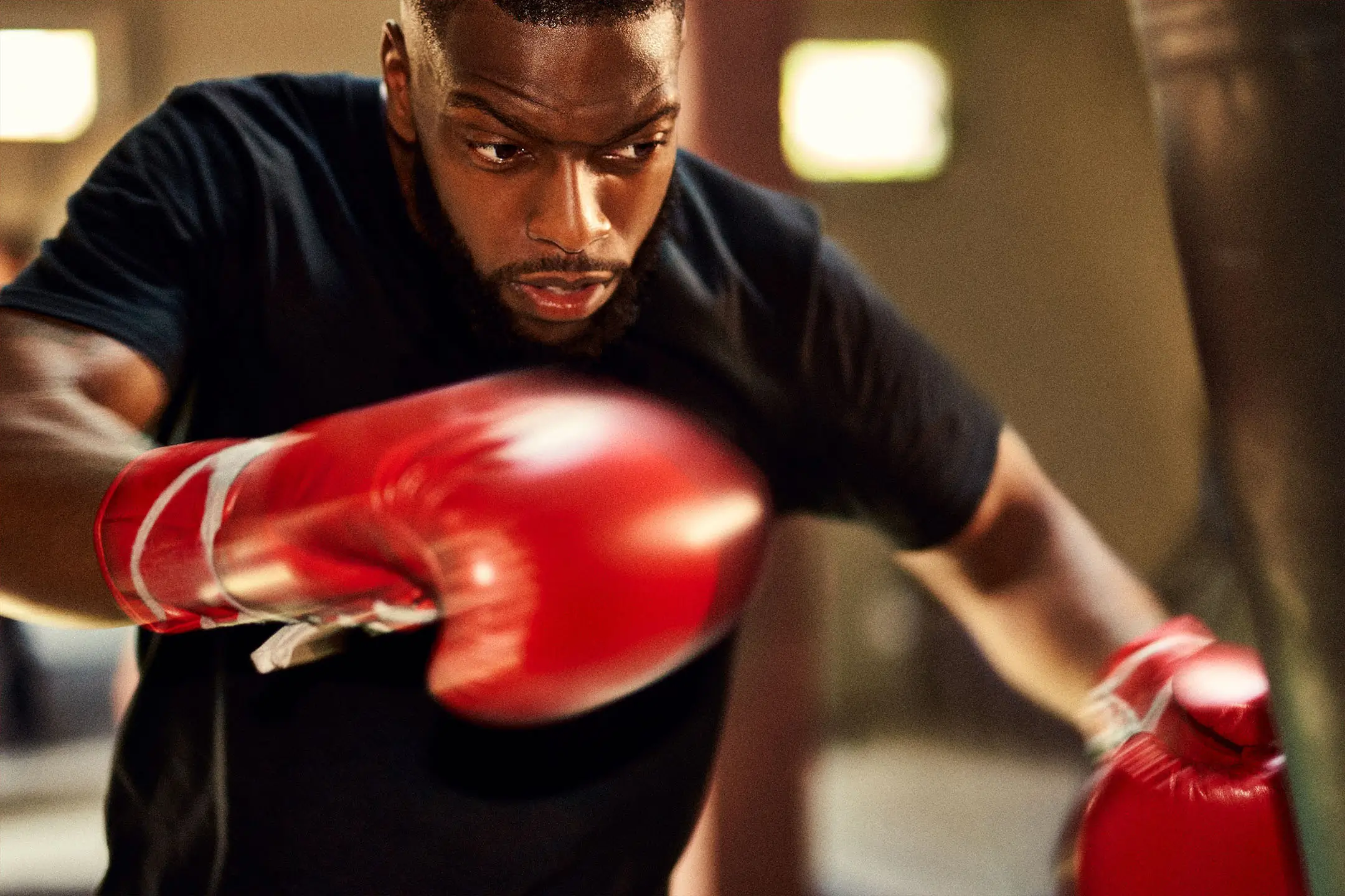Focused man wearing red boxing gloves throwing a punch during training.