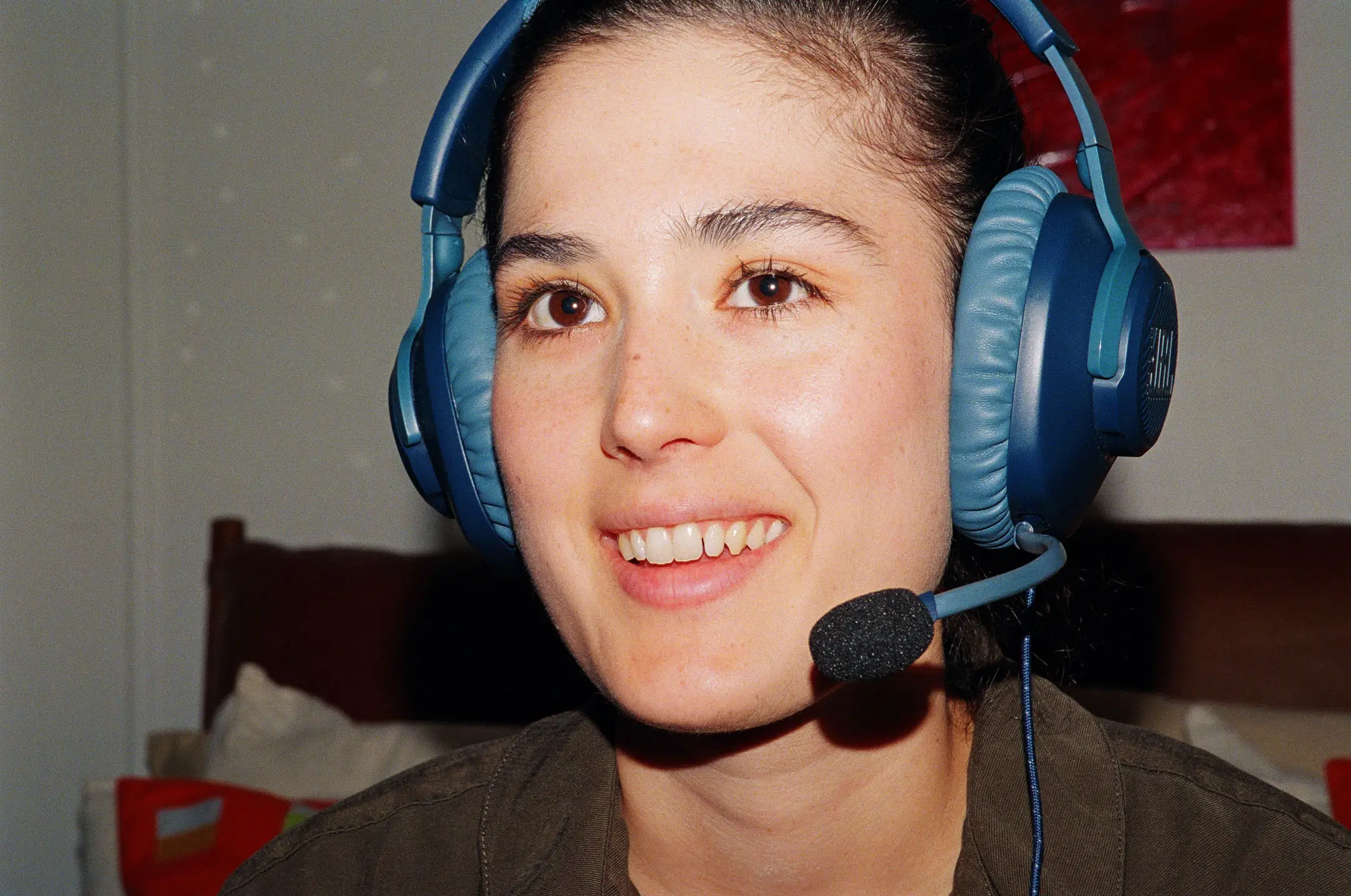 Close-up of a smiling person wearing a blue headset with a microphone.