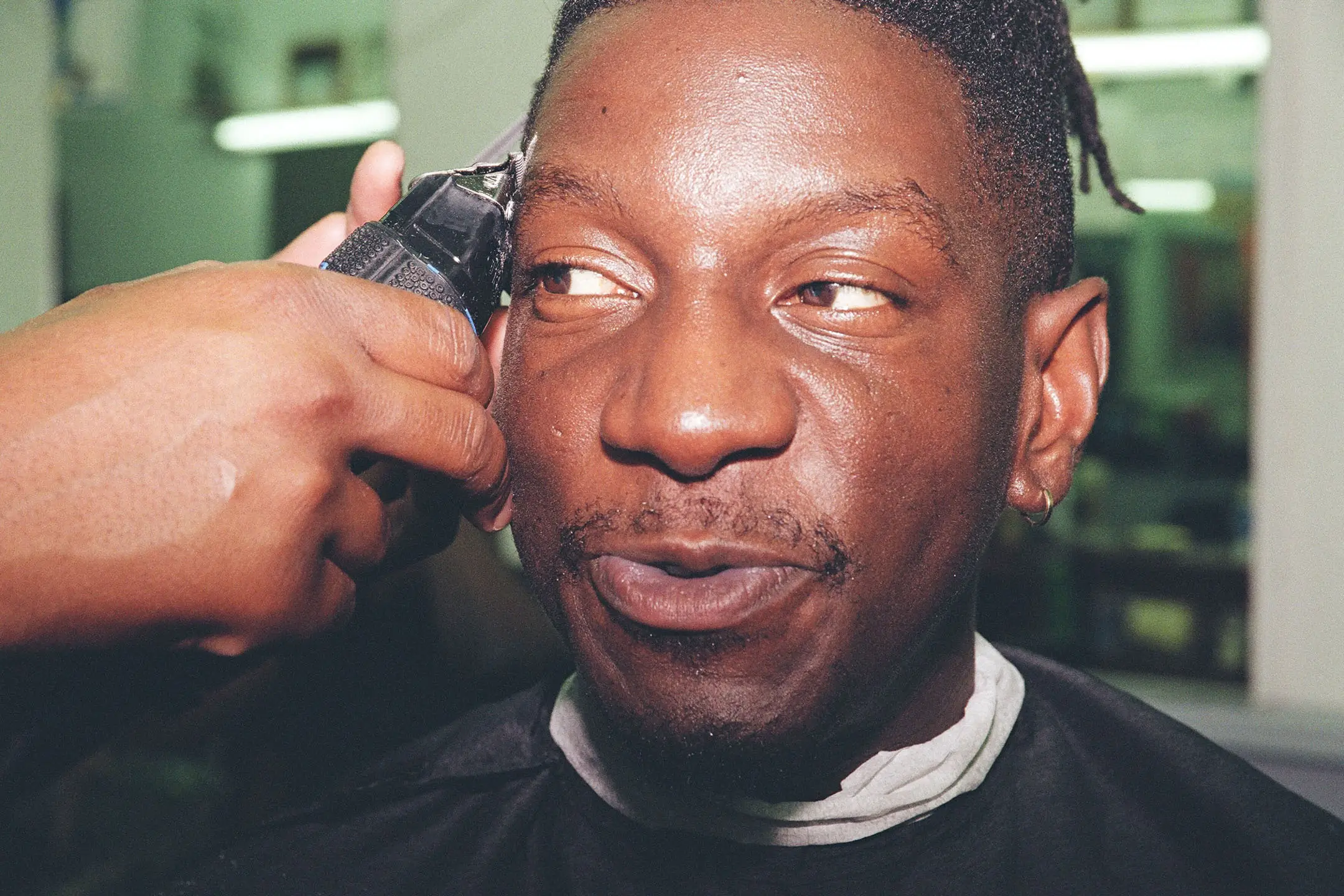 Close-up of a man getting a haircut with clippers at a barber shop.