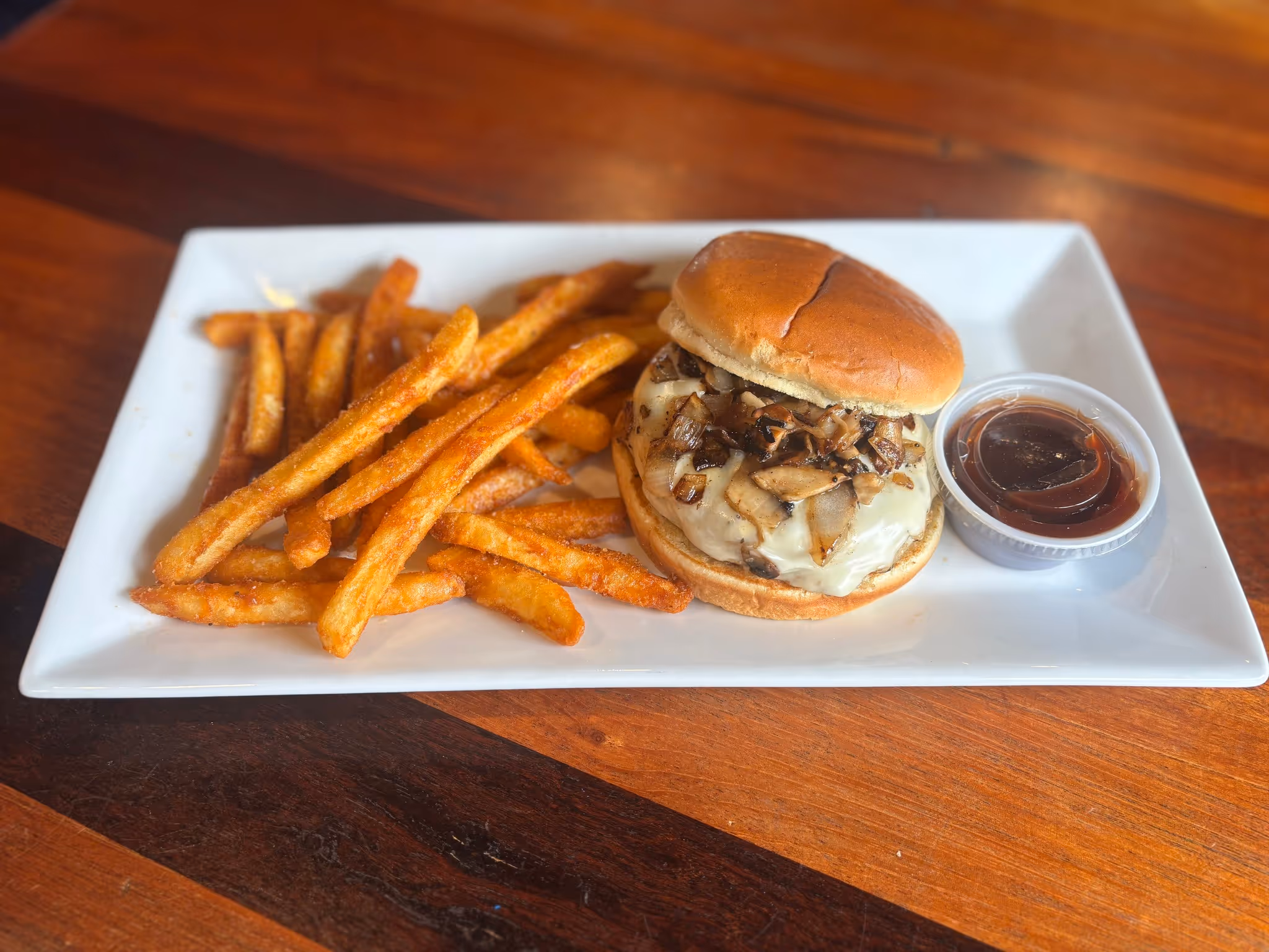 A sandwich with mushrooms and french fries on a white plate.