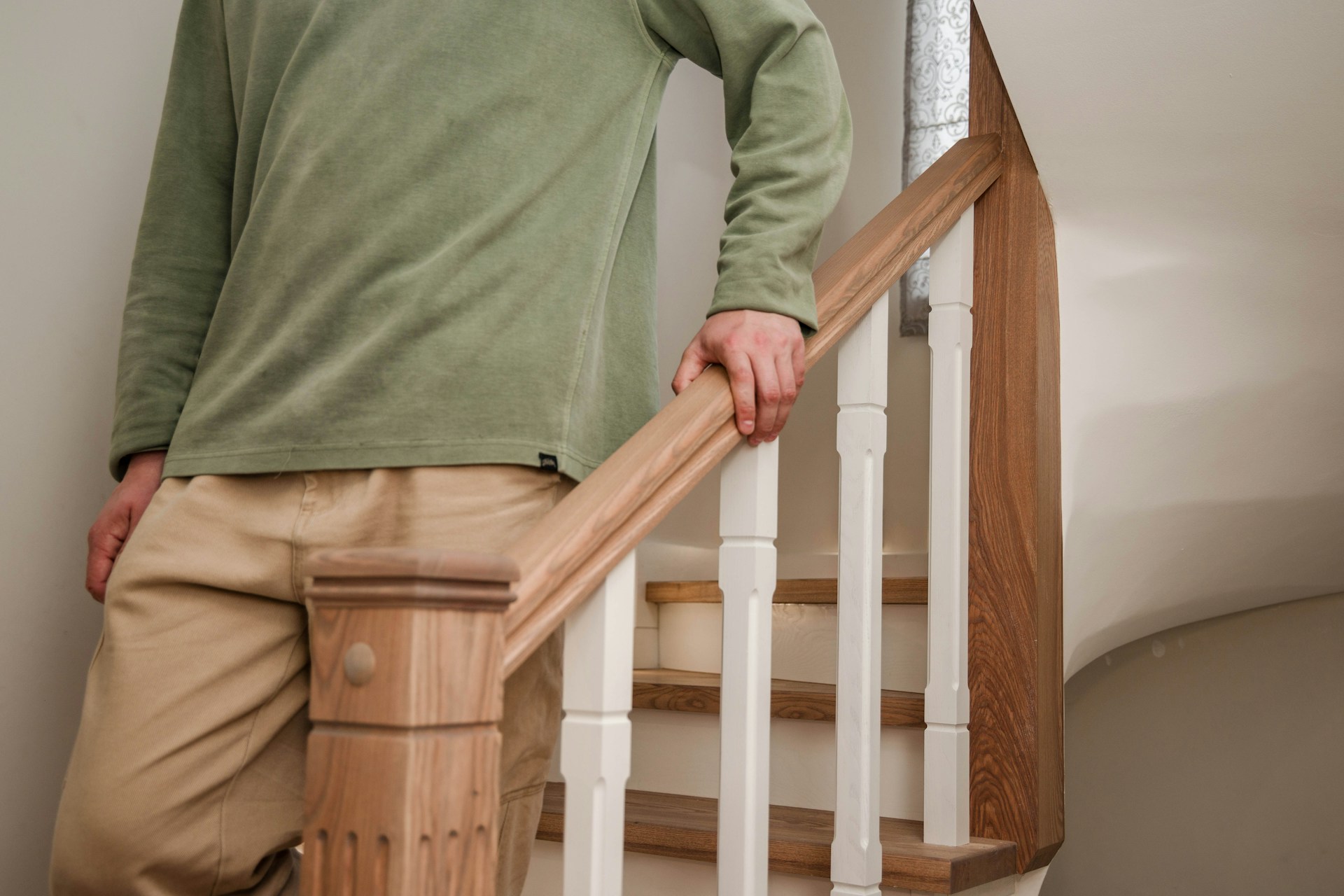 Man walking down a set of stairs with  his hand on the hand rails.