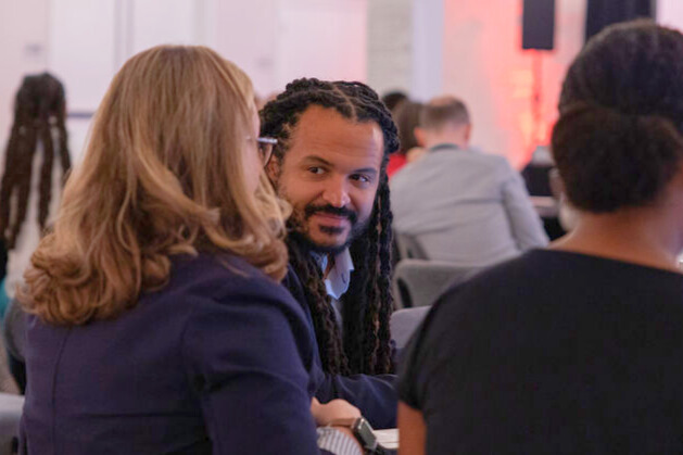 Professionals conversing at crowded indoor event.