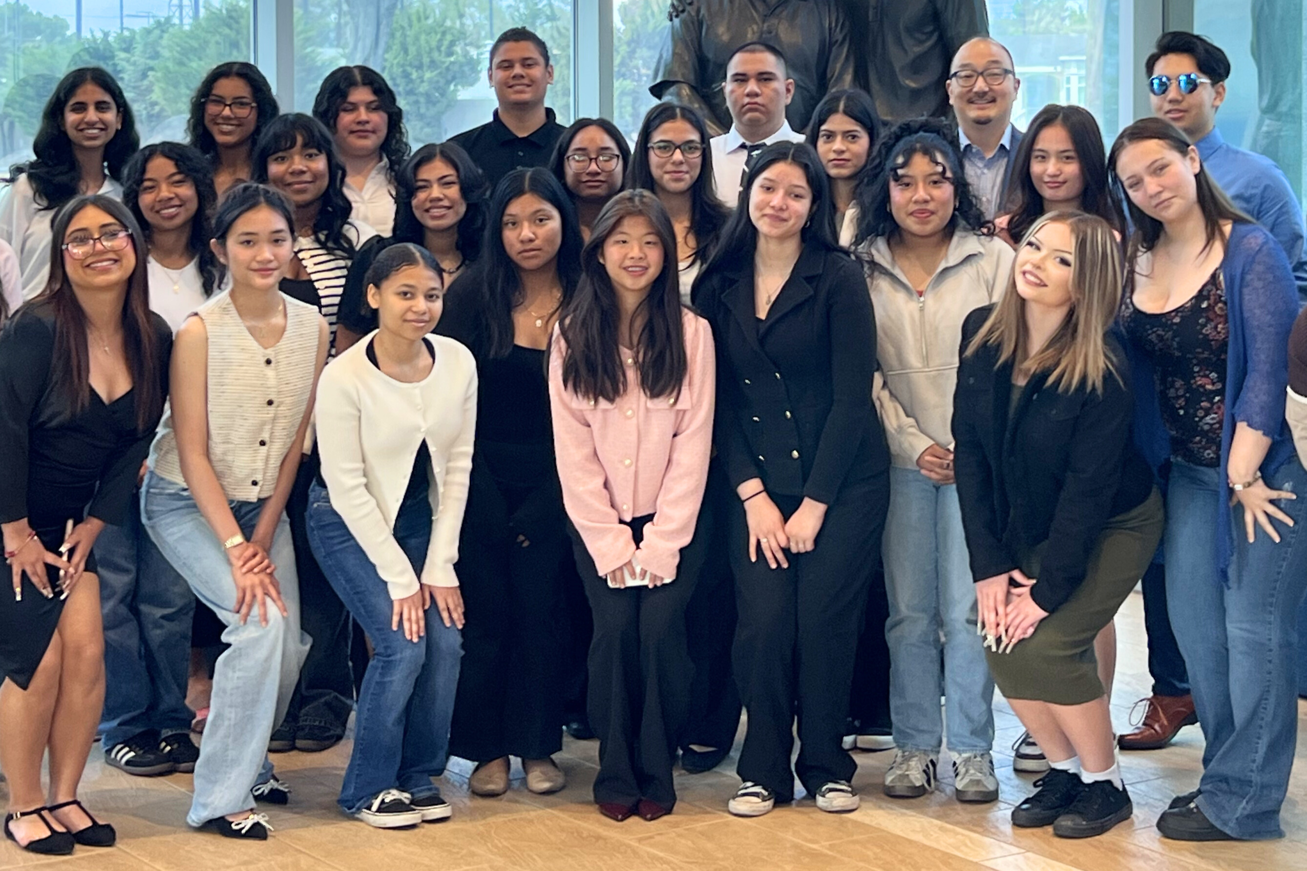 Large group of students posing together in modern office building with windows