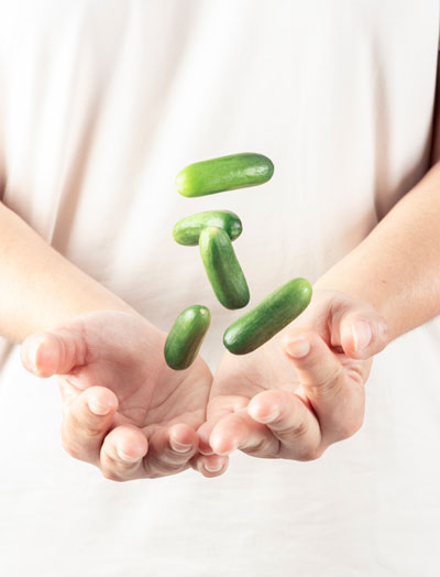 Blue plate with a colorful salad of corn, red bell peppers, green tomatoes, red onion slices, and leafy greens on a peach background.