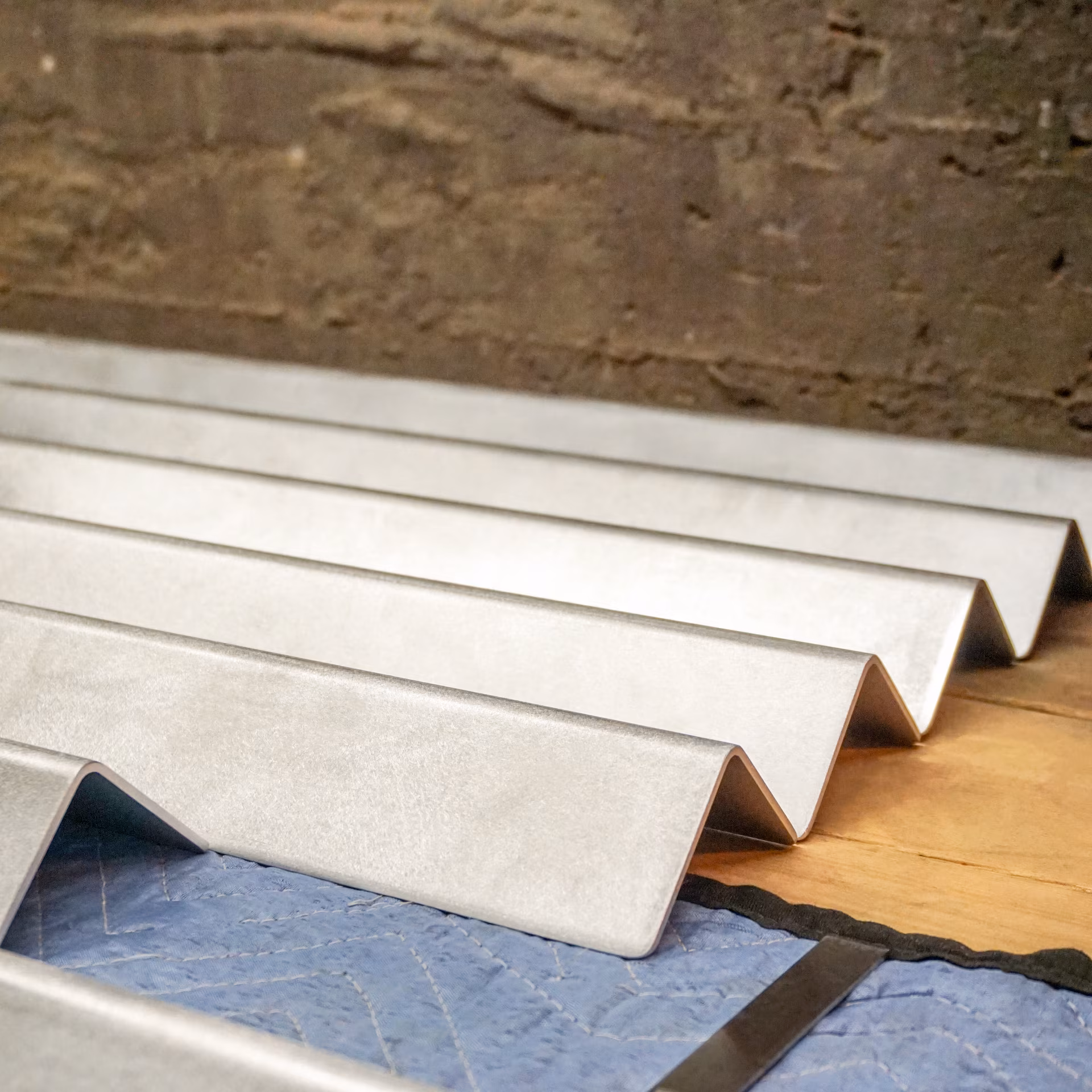 Panneaux métalliques ondulés posés sur un tissu de protection bleu avec un mur en arrière-plan.