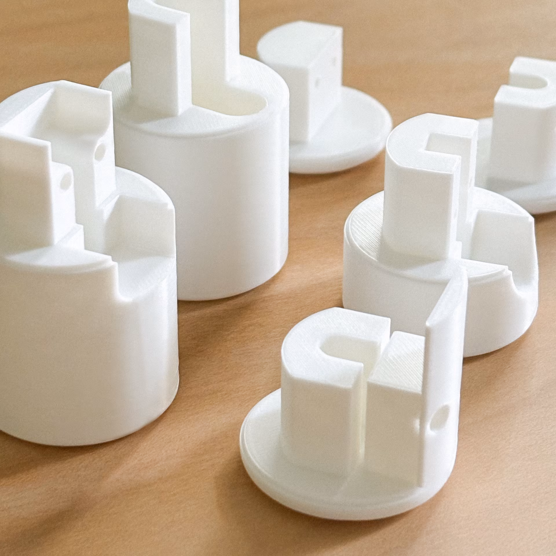Plusieurs pièces blanches en plastique aux formes géométriques posées sur une surface en bois clair.