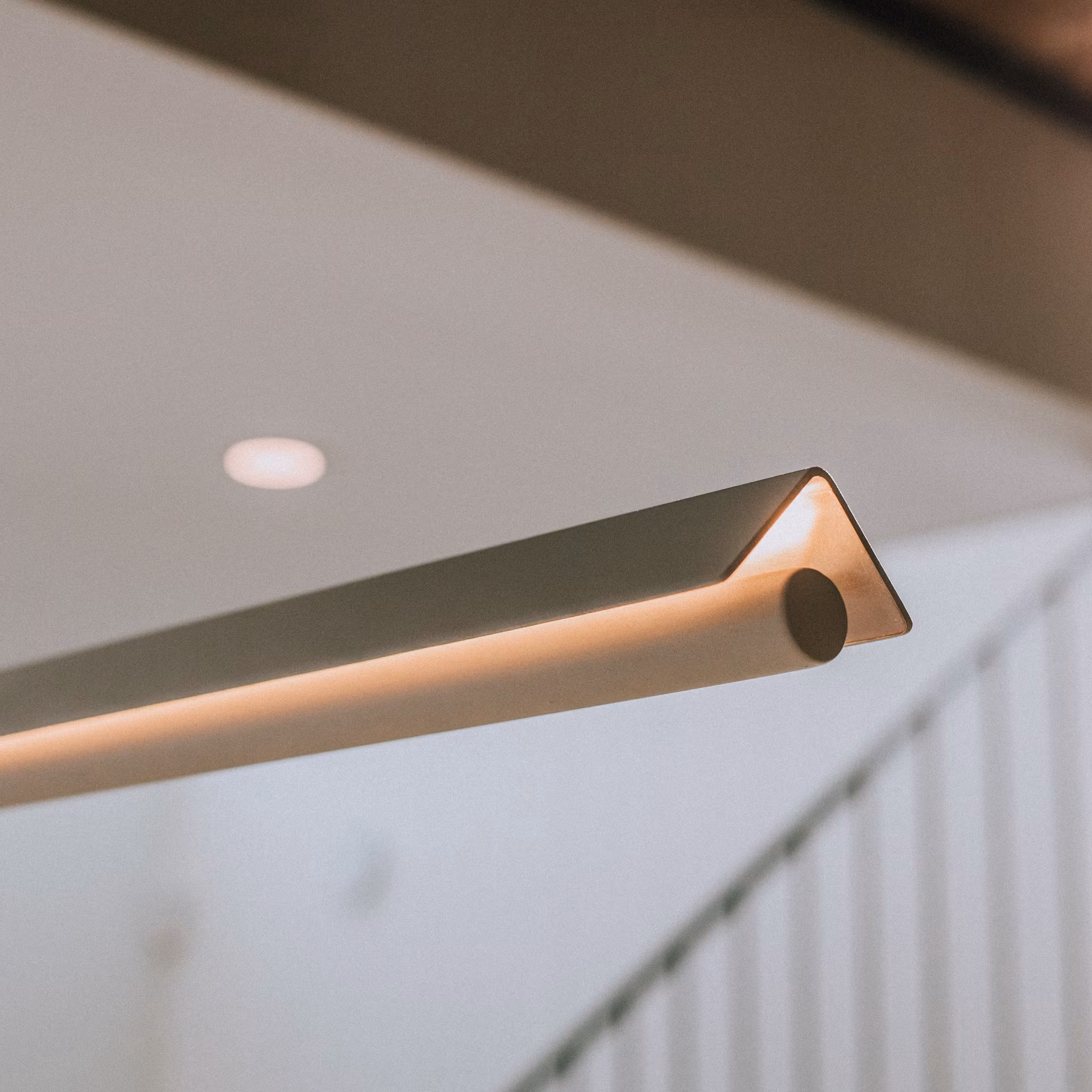 Lampe suspendue moderne avec un design triangulaire éclaire un plafond intérieur.