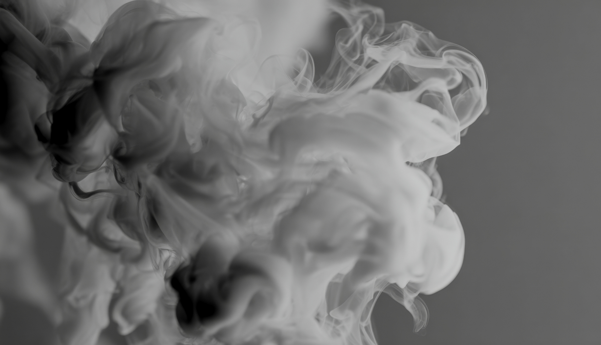 Swirling gray and white smoke forming abstract patterns against a gray background.