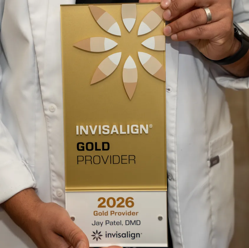 Person in white coat holding Invisalign Gold Provider 2026 plaque for Jay Patel, DMD