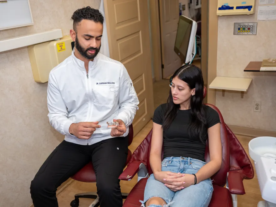 Dentist showing a dental mold to a seated female patient in a dental office.
