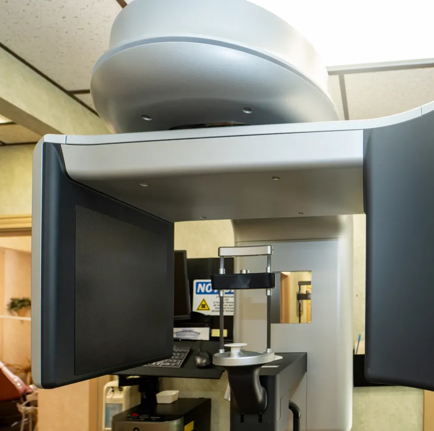 Dental 3D imaging machine with arm and screen panels inside a clinic room.