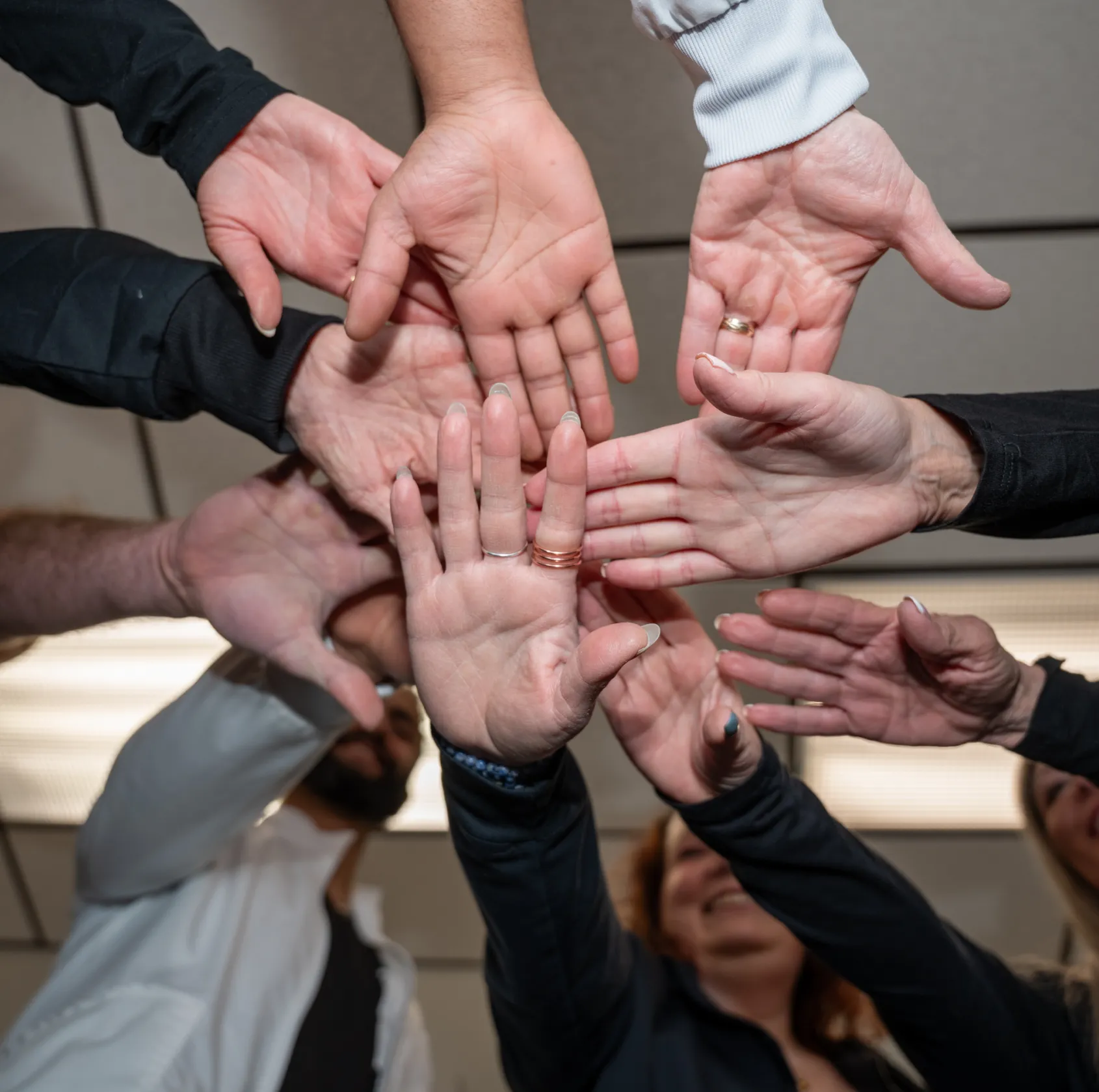 Group of people with hands overlapping in center as a sign of teamwork and unity.