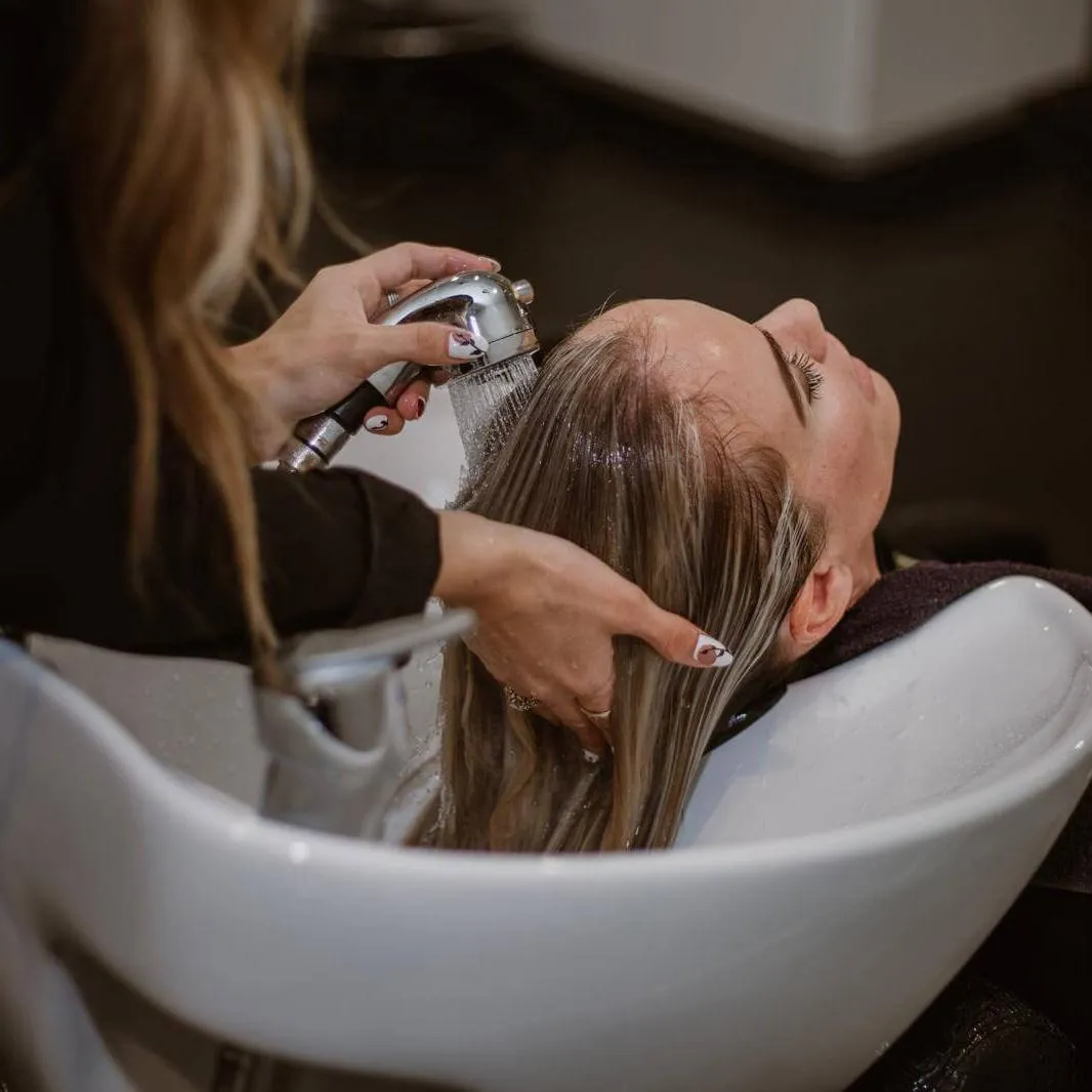 a woman getting her hair cut by a hair stylist
