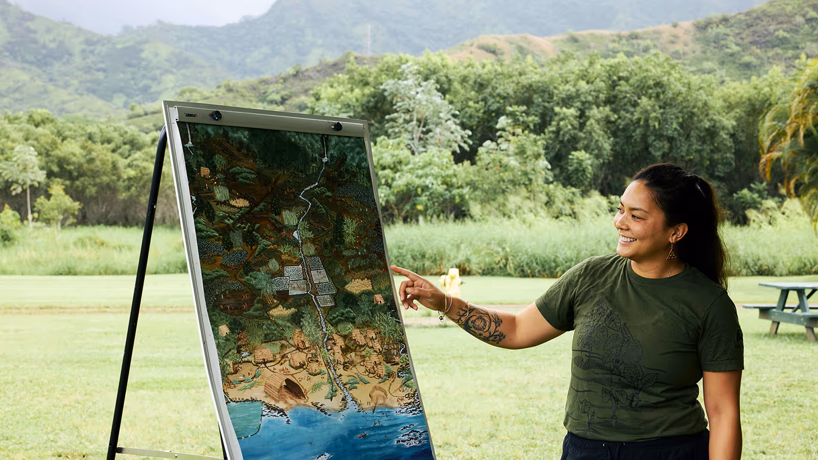 Person pointing at an old map with lush green forest in the background