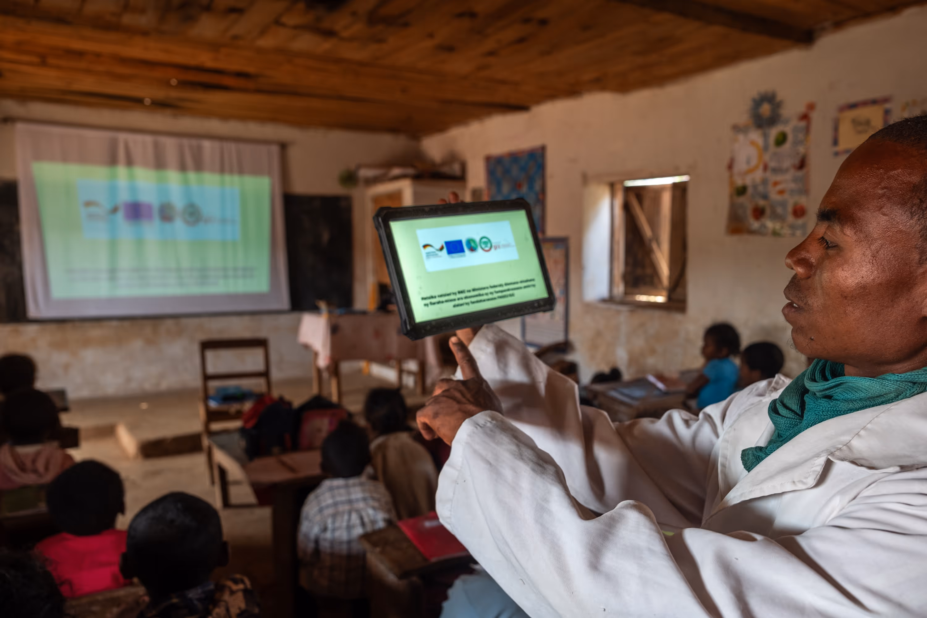 A teacher using a tablet to project a presentation for the class.