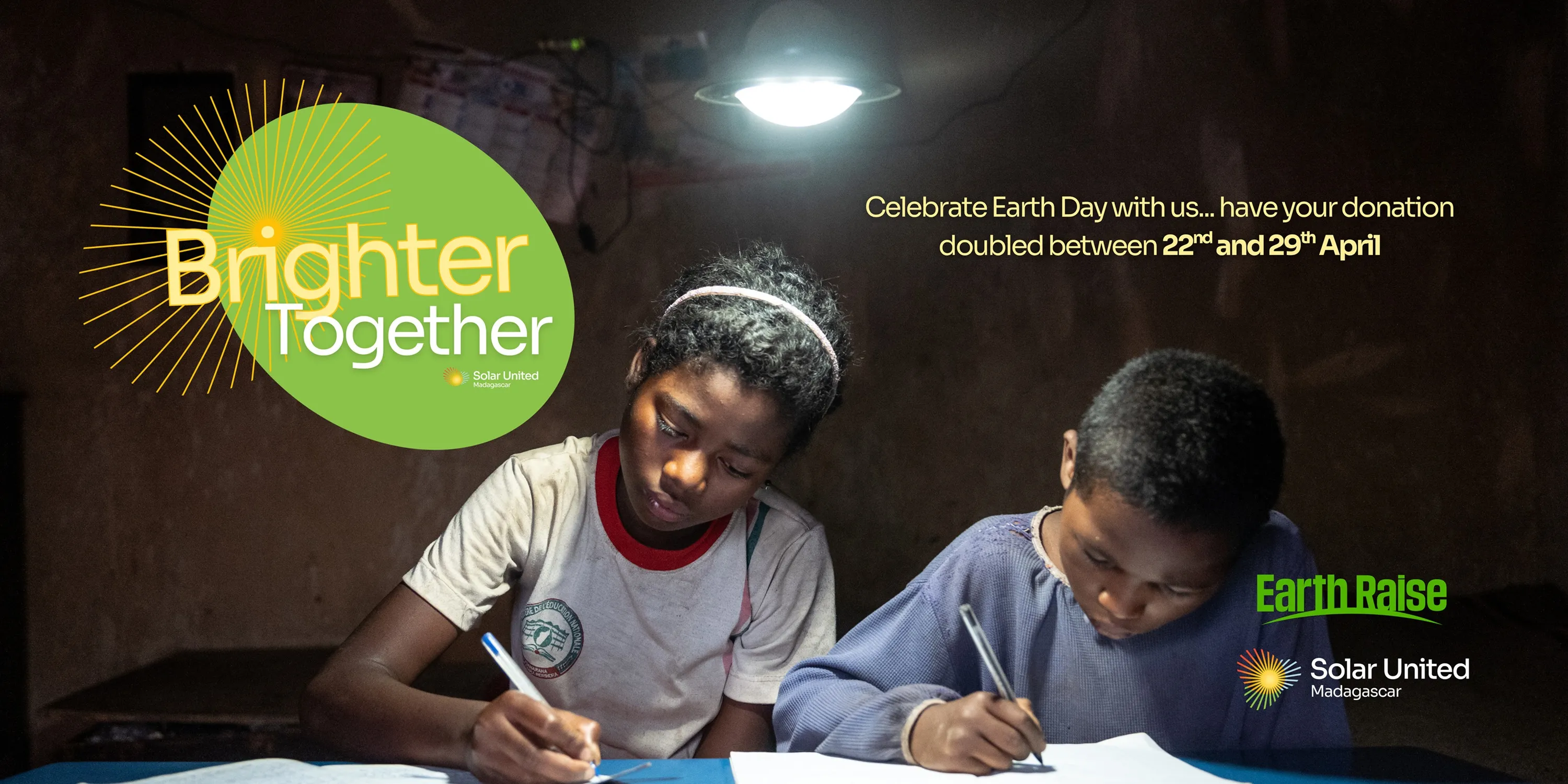 Two children writing below solar powered lamp