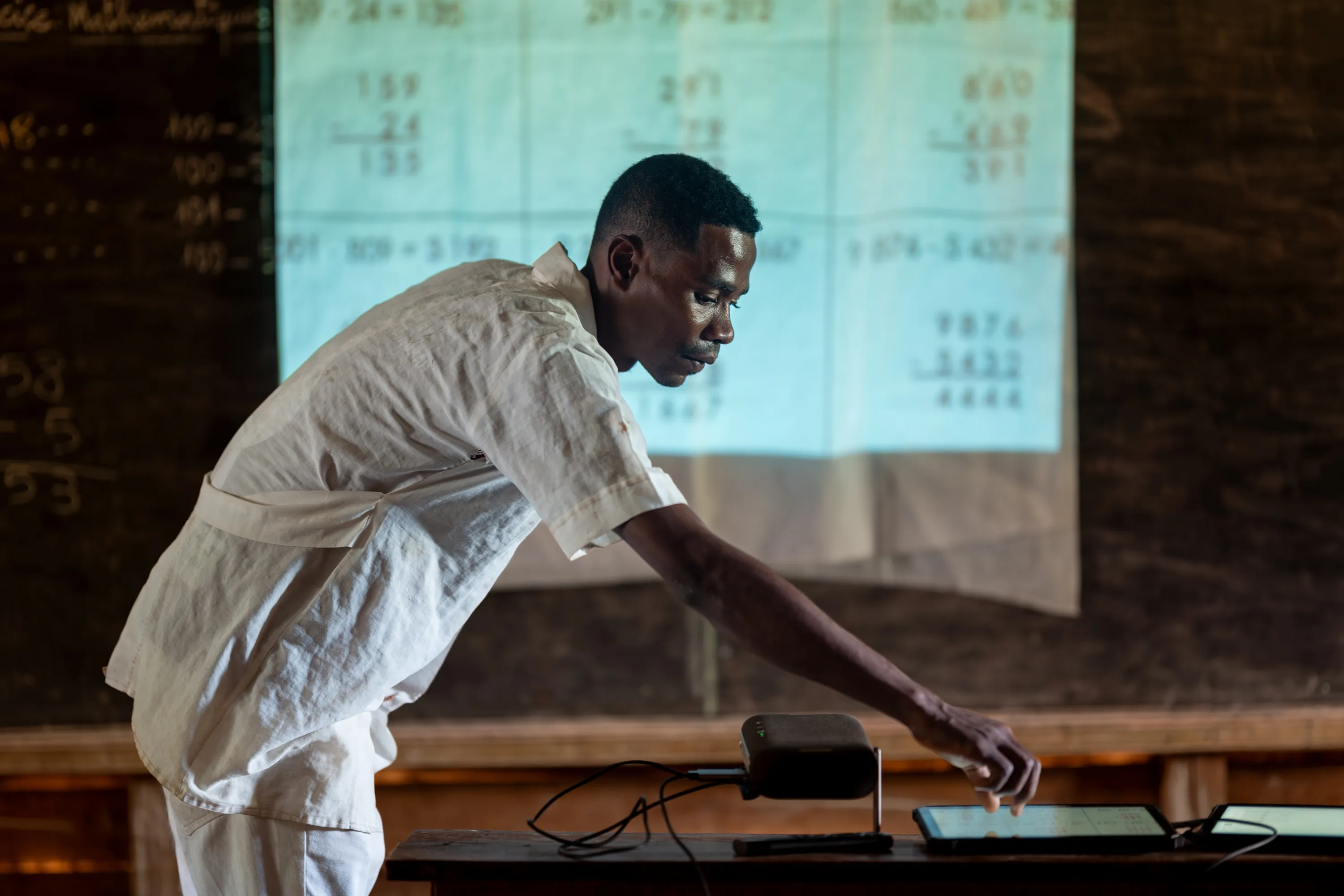 Teacher Espérant uses a tablet connected to a projector to deliver a math lesson to his students, Emagnevy Primary School, Madagascar