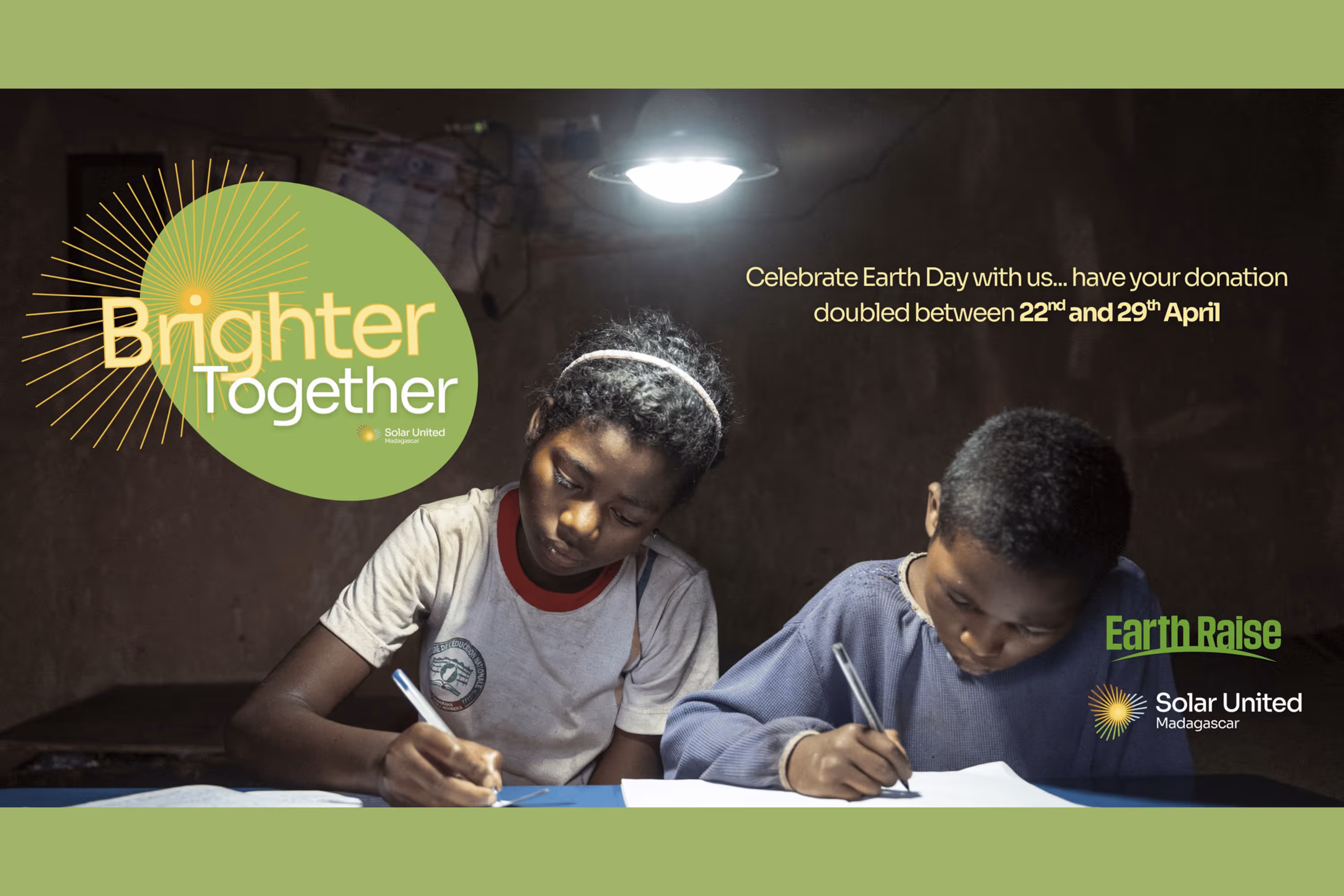 Two children writing below solar powered lamp