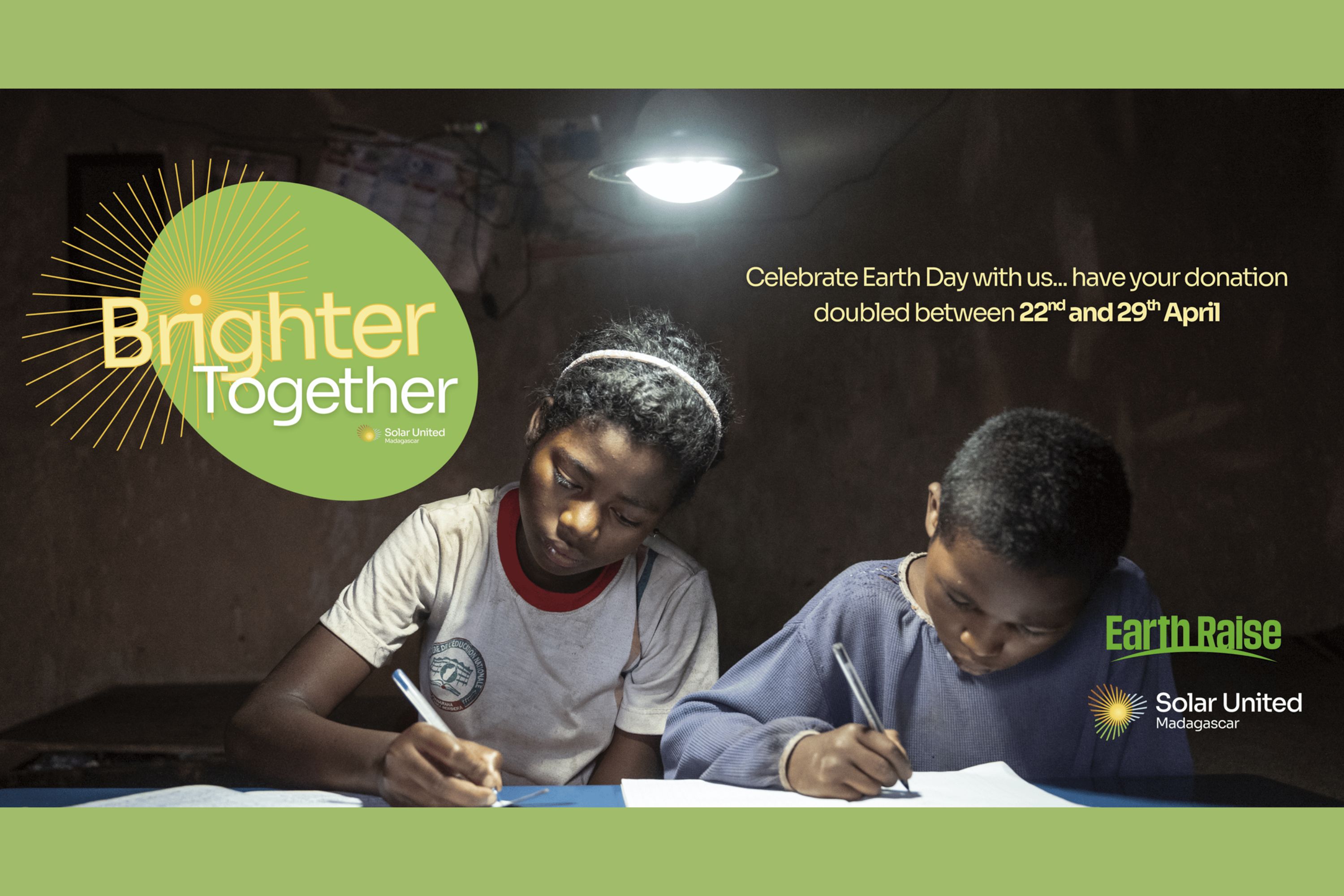 Two children writing below solar powered lamp