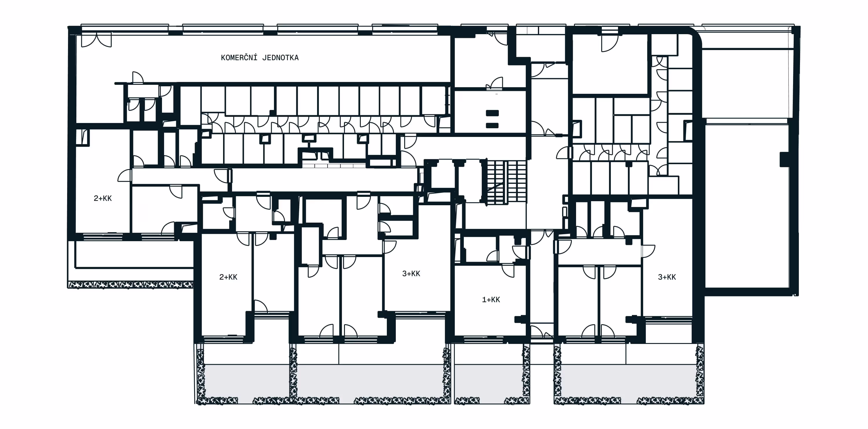 Půdorys prvního nadzemního patra obytné budovy s byty označenými 1+KK, 2+KK a 3+KK a komerční jednotkou.