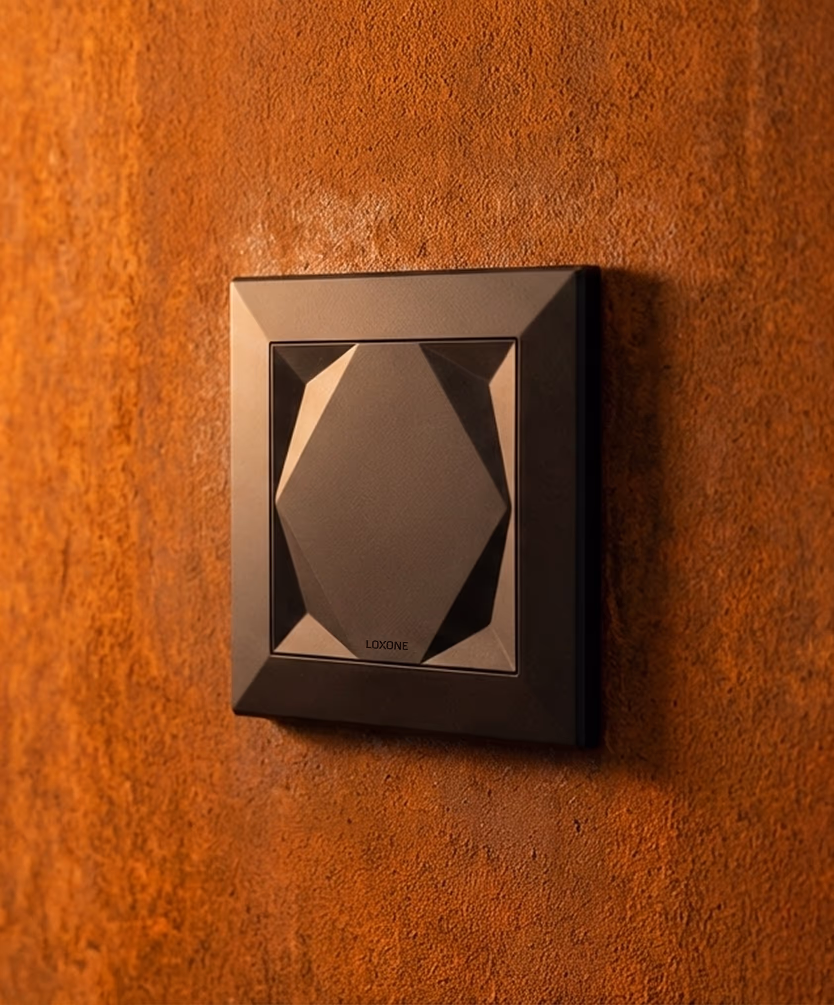 Černý designový vypínač s geometrickým tvarem na rezavé texturované stěně.