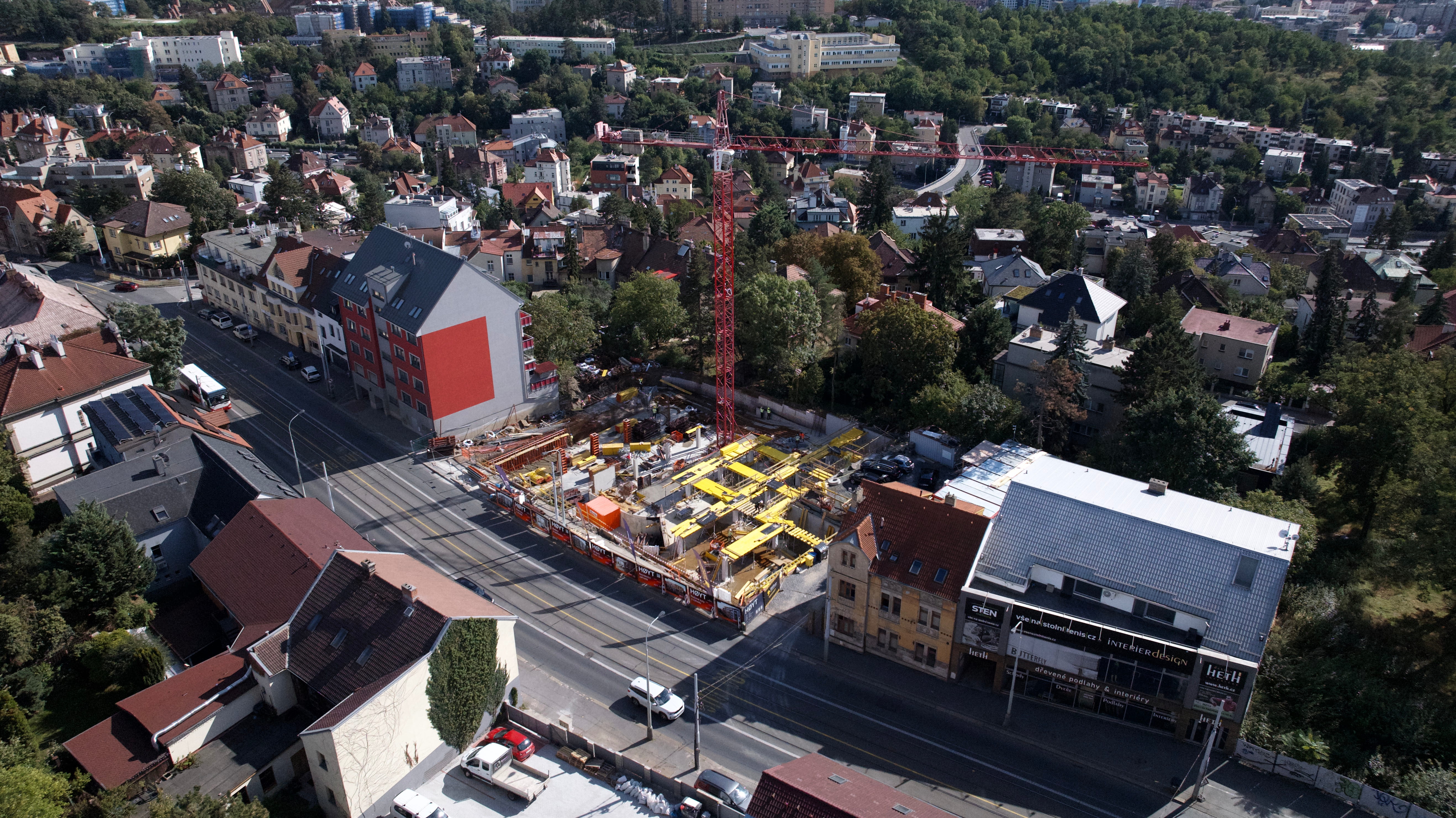 Stavební výkop na zasypaném pozemku s dřevěnou zídkou a stavební technikou za podzimního dne.