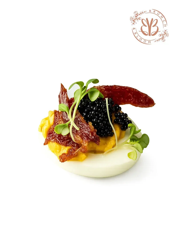 Deviled egg halves made with hot honey chicken, bacon & caviar topped shrimp