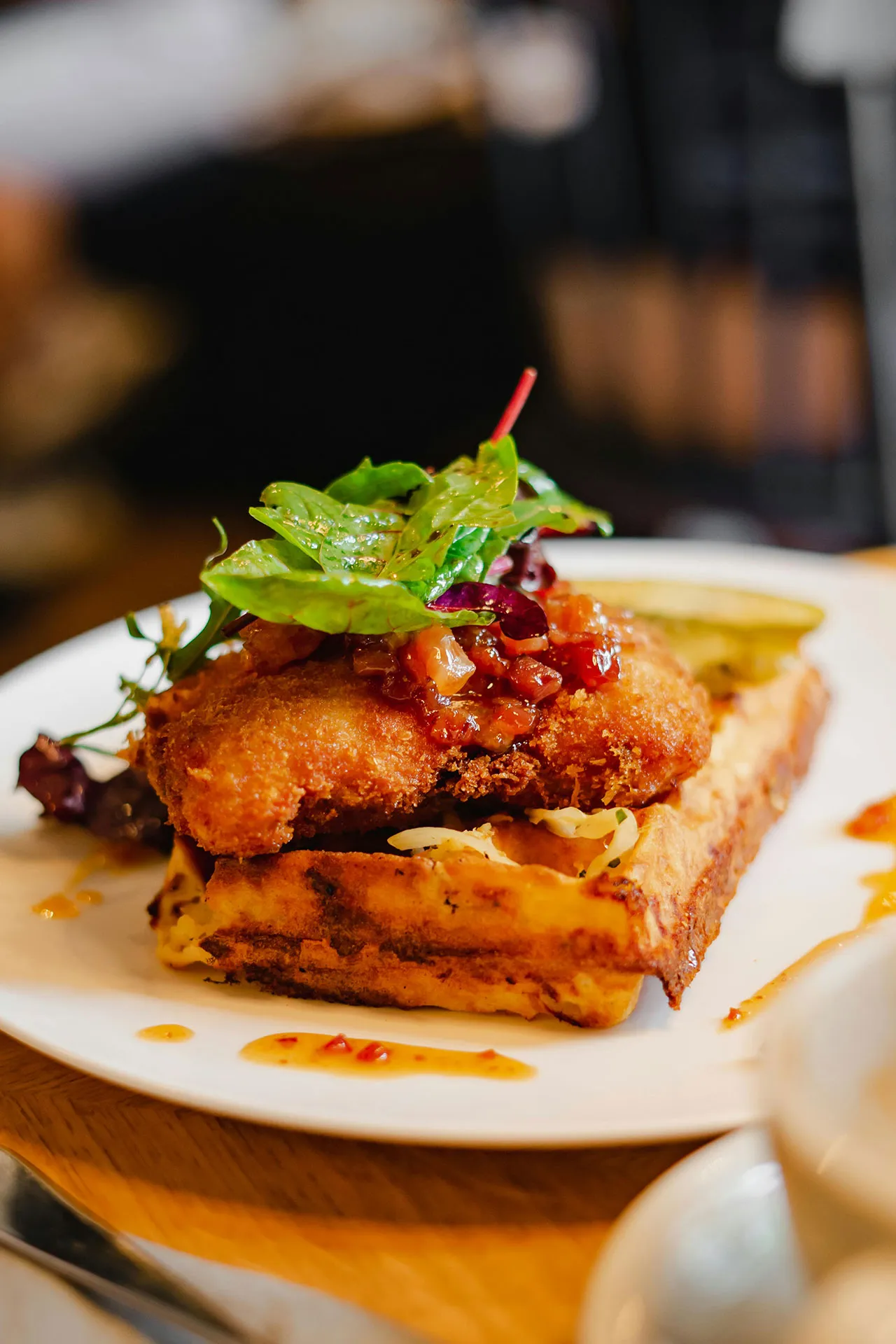 Buttermilk fried chicken over a belgian waffle with maple syrup & a honey drizzle
