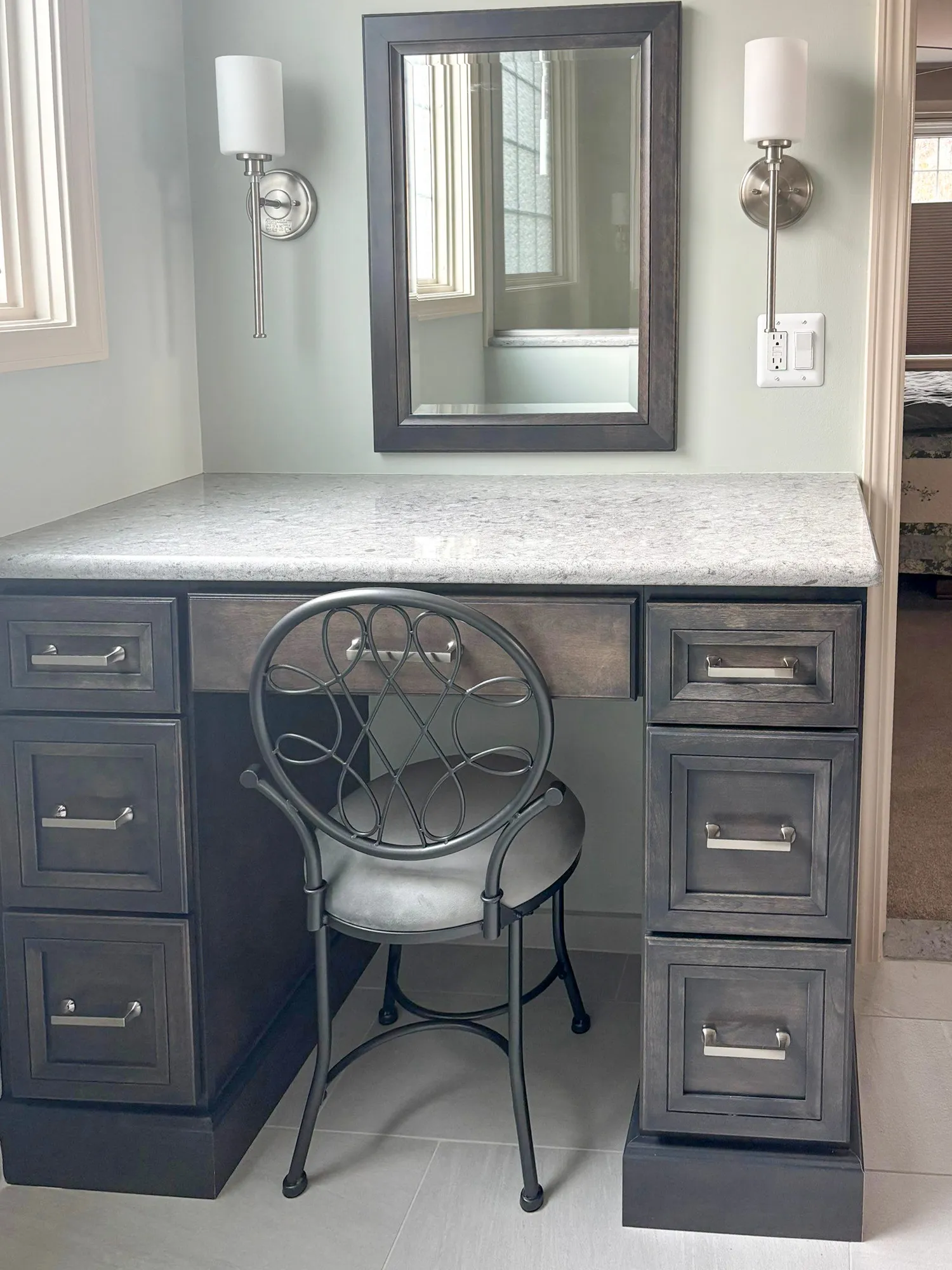 Vanity desk with mirror, metal chair, and wall sconces