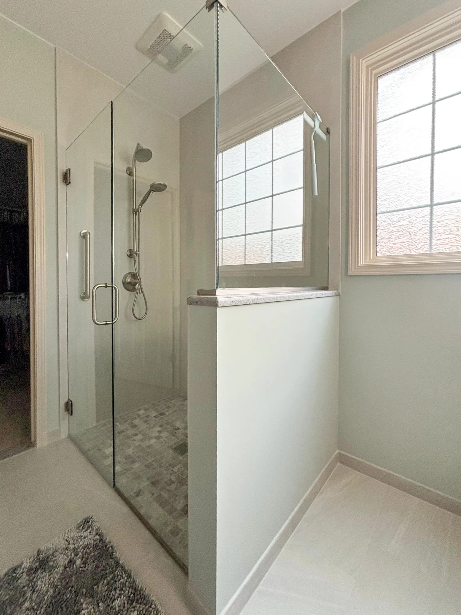 Glass shower with tile floor and window nearby